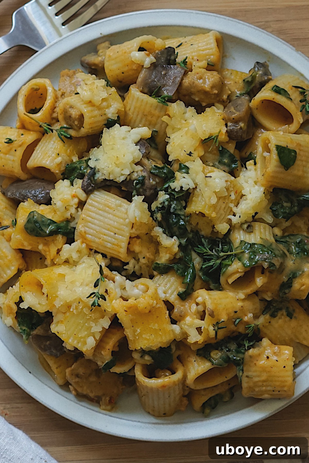 Golden Pumpkin Pasta Casserole 4 A close-up shot of the cooked rigatoni pasta mixed with the creamy pumpkin sauce, kale, and vegan sausage, before being topped with cheese and baked.