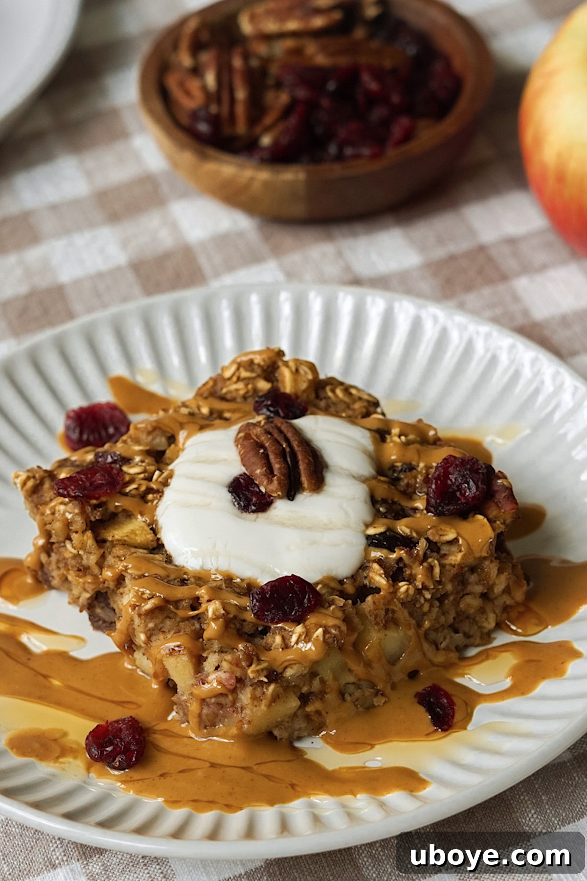 Baked Apple Cinnamon Oats 8 A neatly sliced piece of apple cinnamon baked oatmeal on a white plate, drizzled with sweet maple syrup and garnished