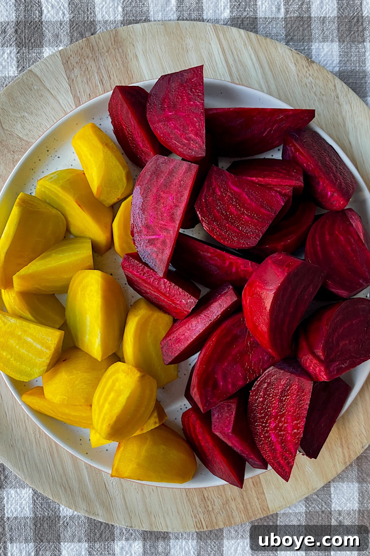 Hands carefully peeling a fresh, uncooked beet over a cutting board
