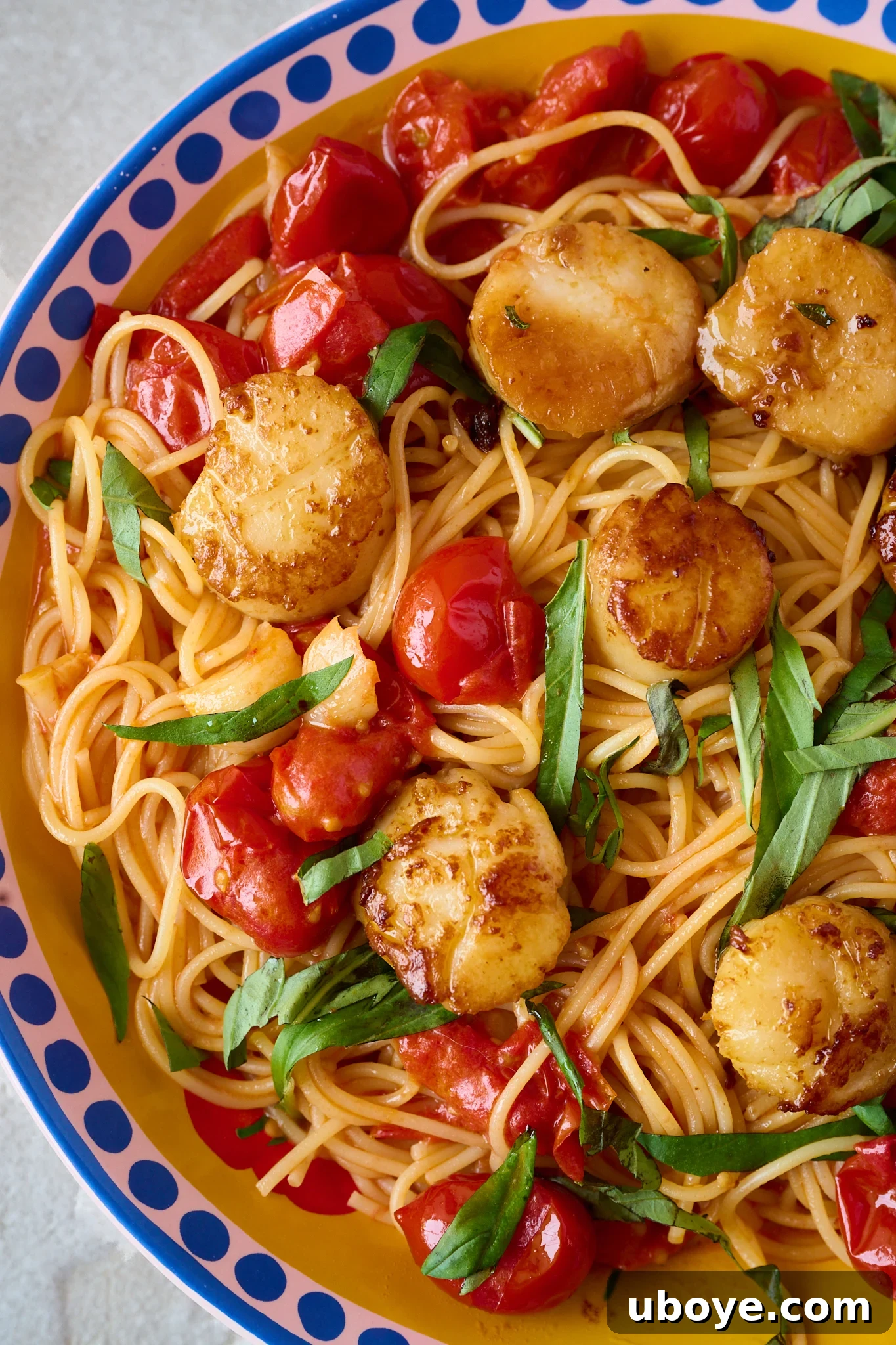 Brown Butter Scallop Pasta with Blistered Cherry Tomatoes 2 Perfectly seared scallops resting on a bed of cherry tomato pasta in a bowl with fresh basil scattered over the top.