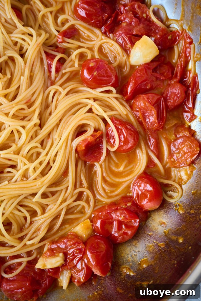 Brown Butter Scallop Pasta with Blistered Cherry Tomatoes 6 Cherry tomatoes bursting and simmering in olive oil and garlic in a pan.