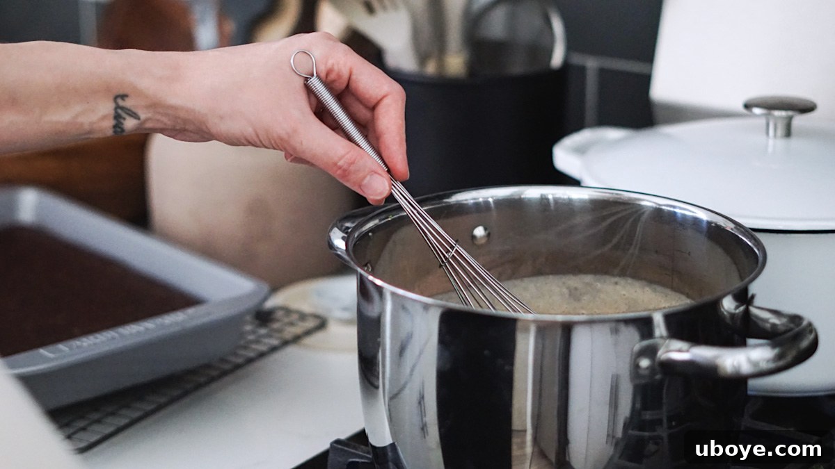 Decadent Chocolate Trifle Made Easy 6 Chocolate pudding being whisked in a saucepan on the stove to achieve a smooth, thick consistency.
