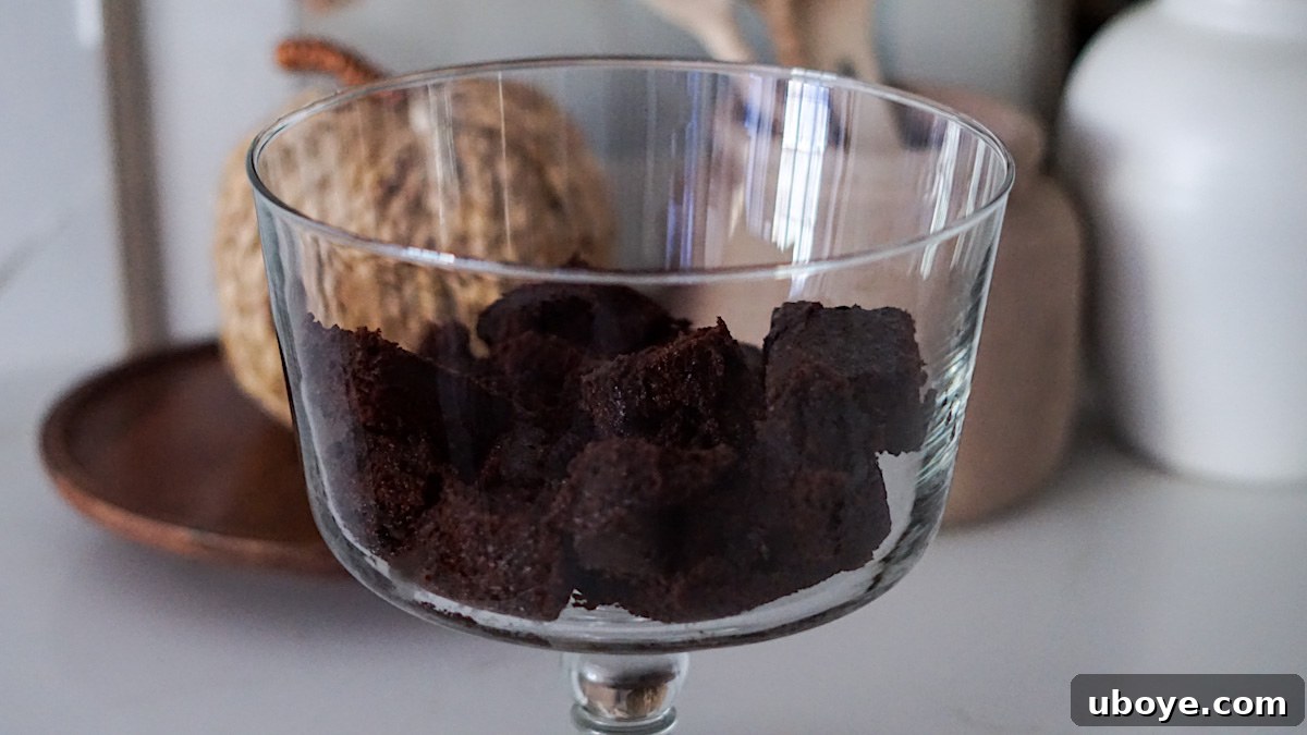 Decadent Chocolate Trifle Made Easy 8 First layer of cubed chocolate cake at the bottom of a glass trifle dish.