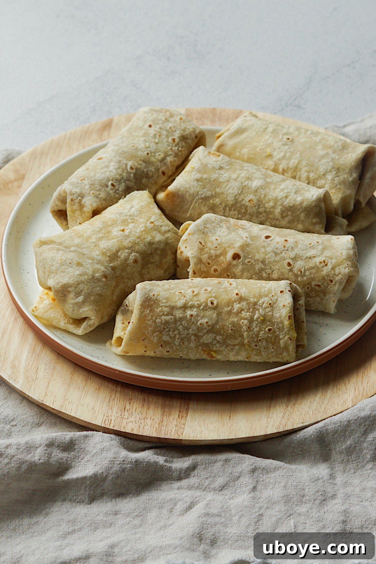 Two golden-brown freezer-friendly breakfast burritos on a white plate, ready to be enjoyed.