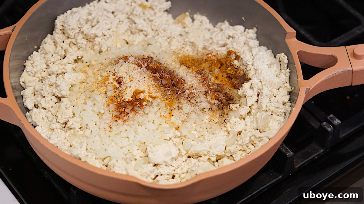 Tofu scramble with spices being prepared in a skillet