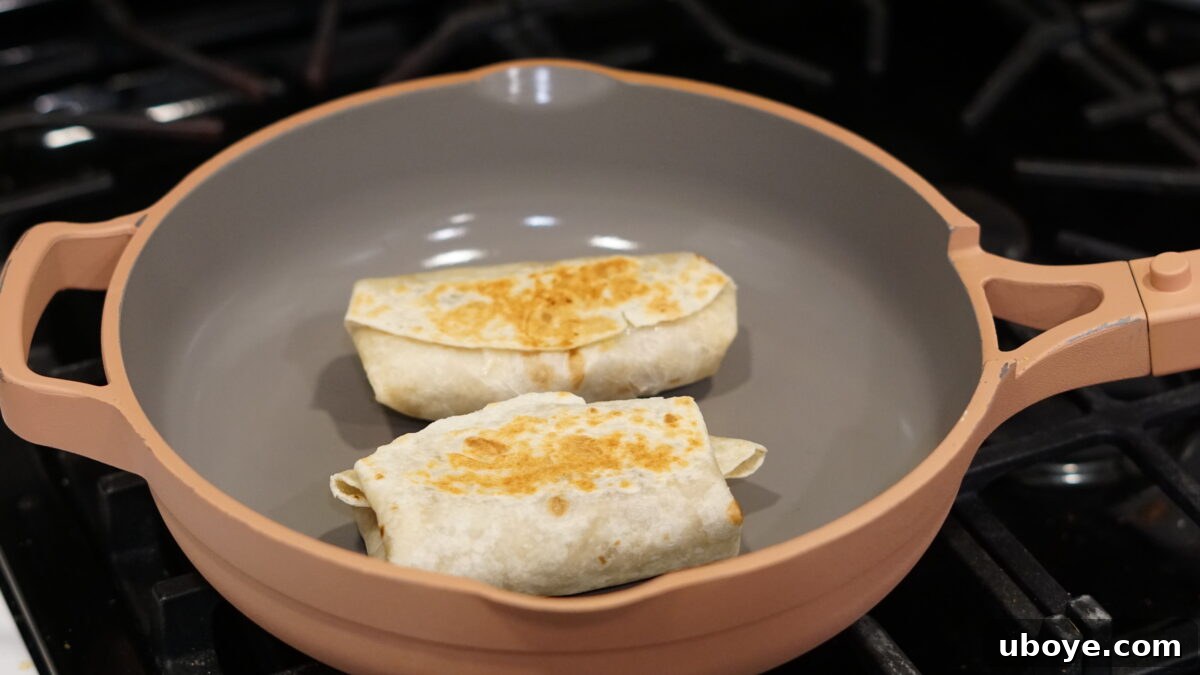 Toasting freshly rolled burritos in a large skillet