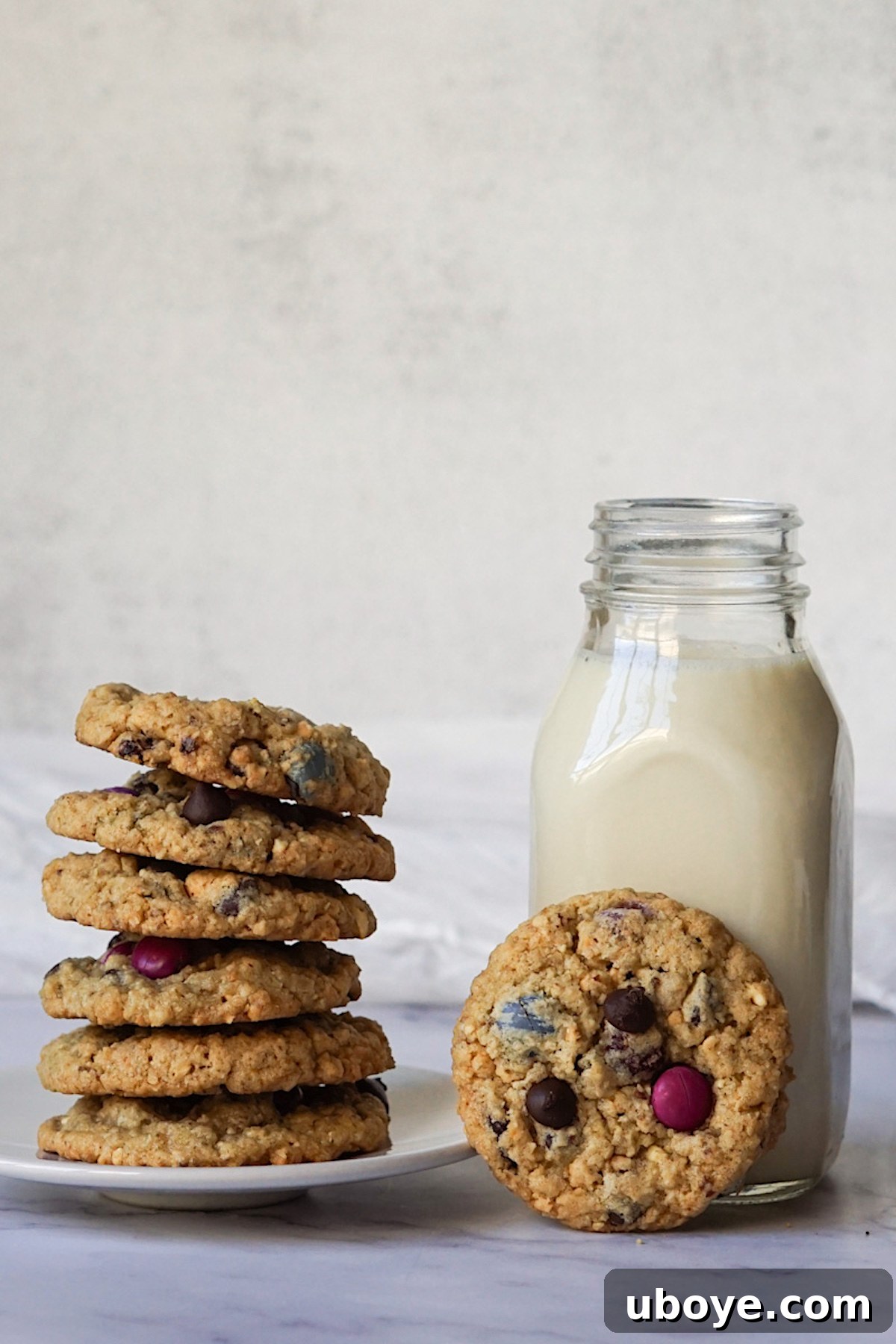 Ultimate Vegan Mix-In Cookies 4 A beautiful arrangement of stacked vegan kitchen sink cookies next to a tall glass of almond milk, ready for enjoyment.