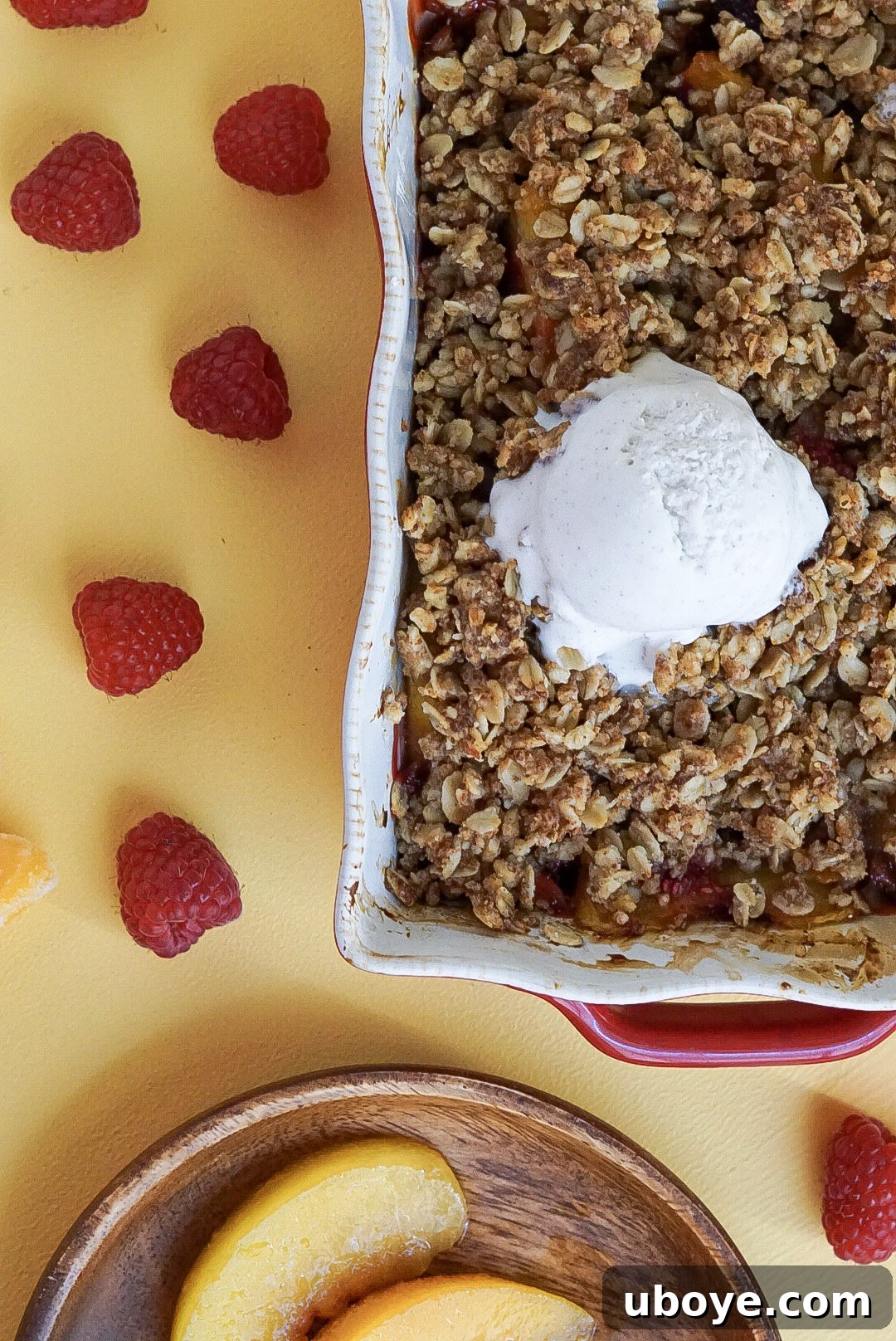 Golden Peach Raspberry Bake 7 A large red baking dish filled with hot vegan peach and raspberry crumble