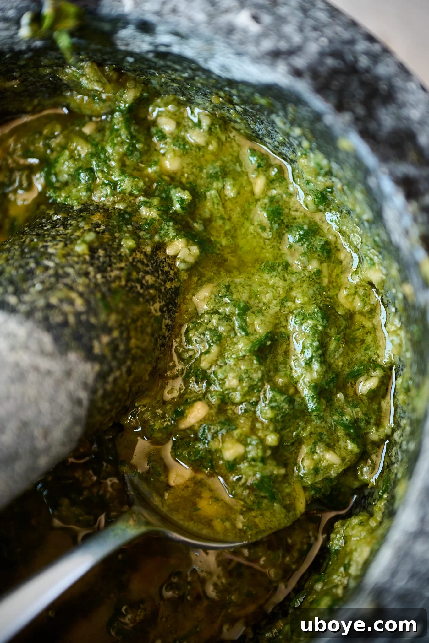 Hand-Crushed Pesto Perfection 2 Freshly made pesto in a black and white mortar and pestle, highlighting its vibrant green color and rustic texture.