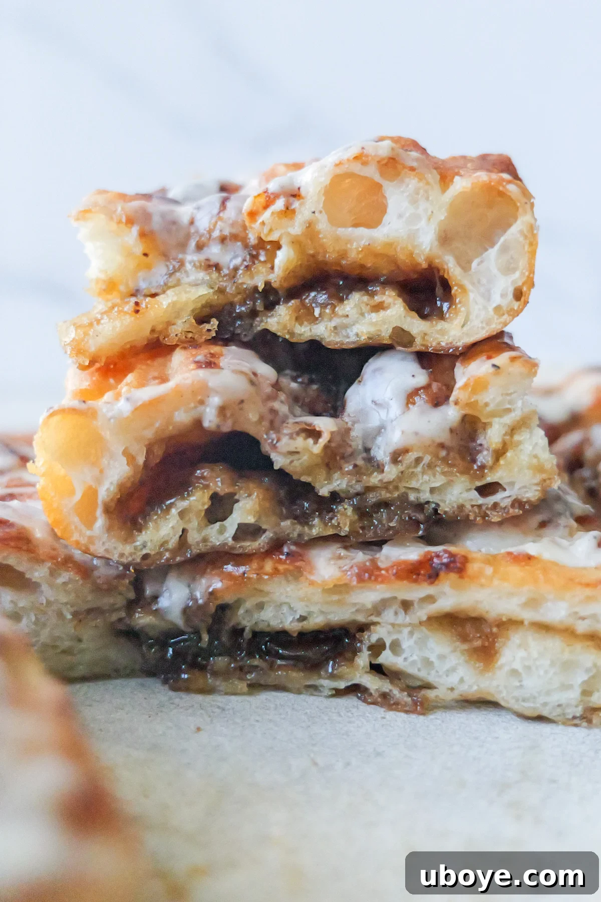 Sweet cinnamon scroll focaccia is presented in neat slices, revealing the luscious brown filling swirled within. Three generous pieces are artfully stacked atop each other, ready to be enjoyed.