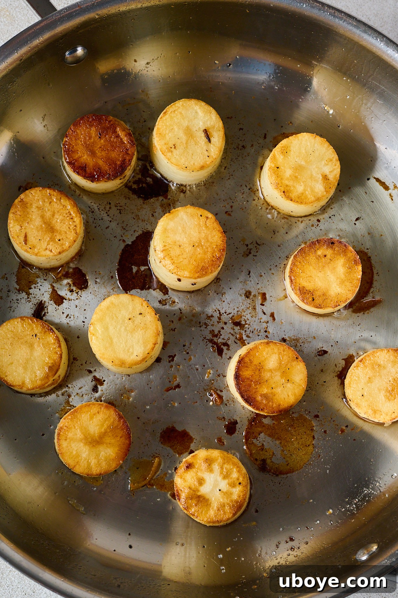 Golden Garlic Thyme Fondant Potatoes 5 Seared potato rounds golden and crispy, arranged in a stainless steel oven-safe pan.