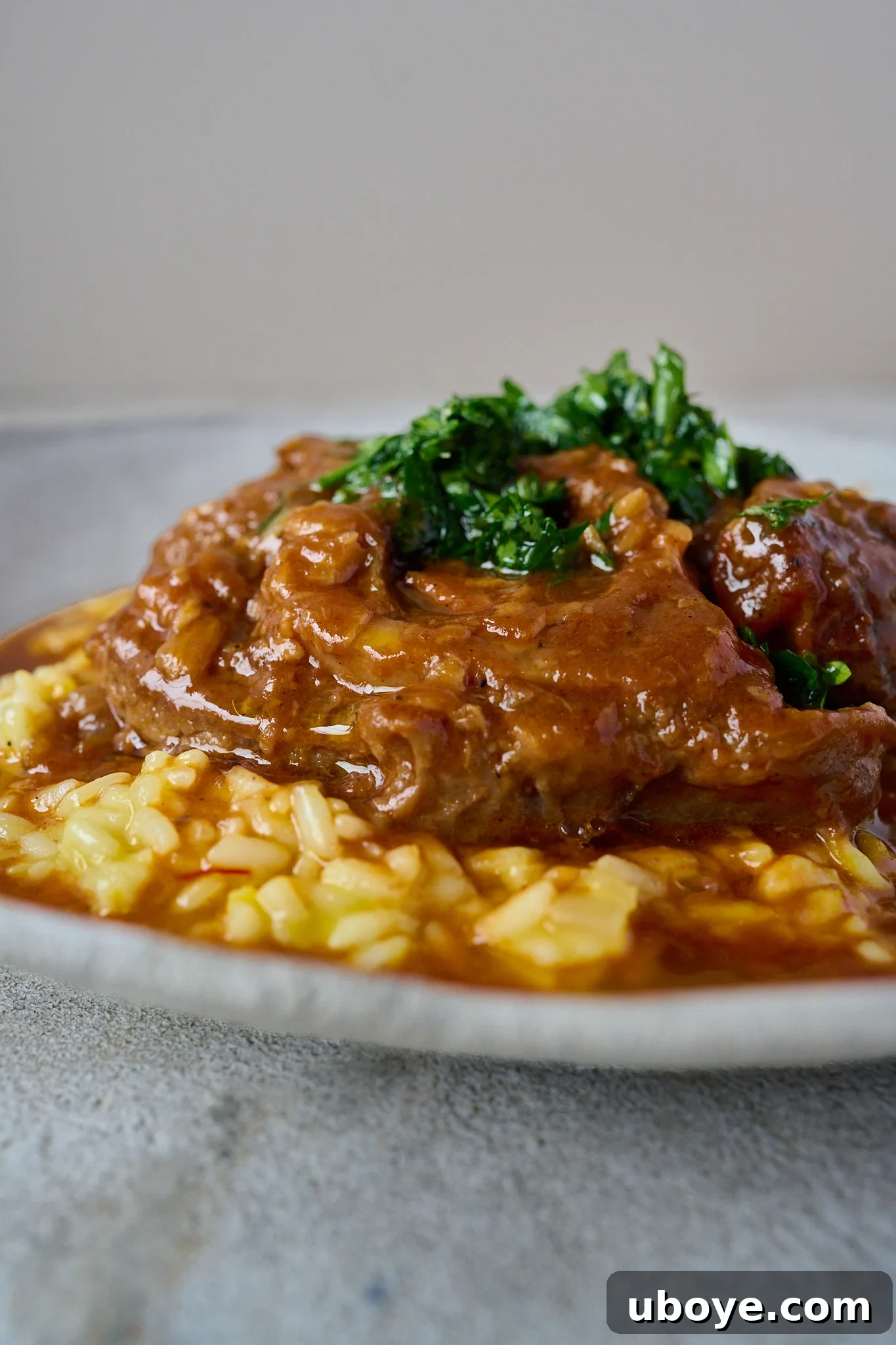 Braised Osso Buco with Zesty Gremolata and Creamy Risotto 12 Another beautiful shot of Osso Buco on saffron risotto, garnished with gremolata, emphasizing its comforting appeal.