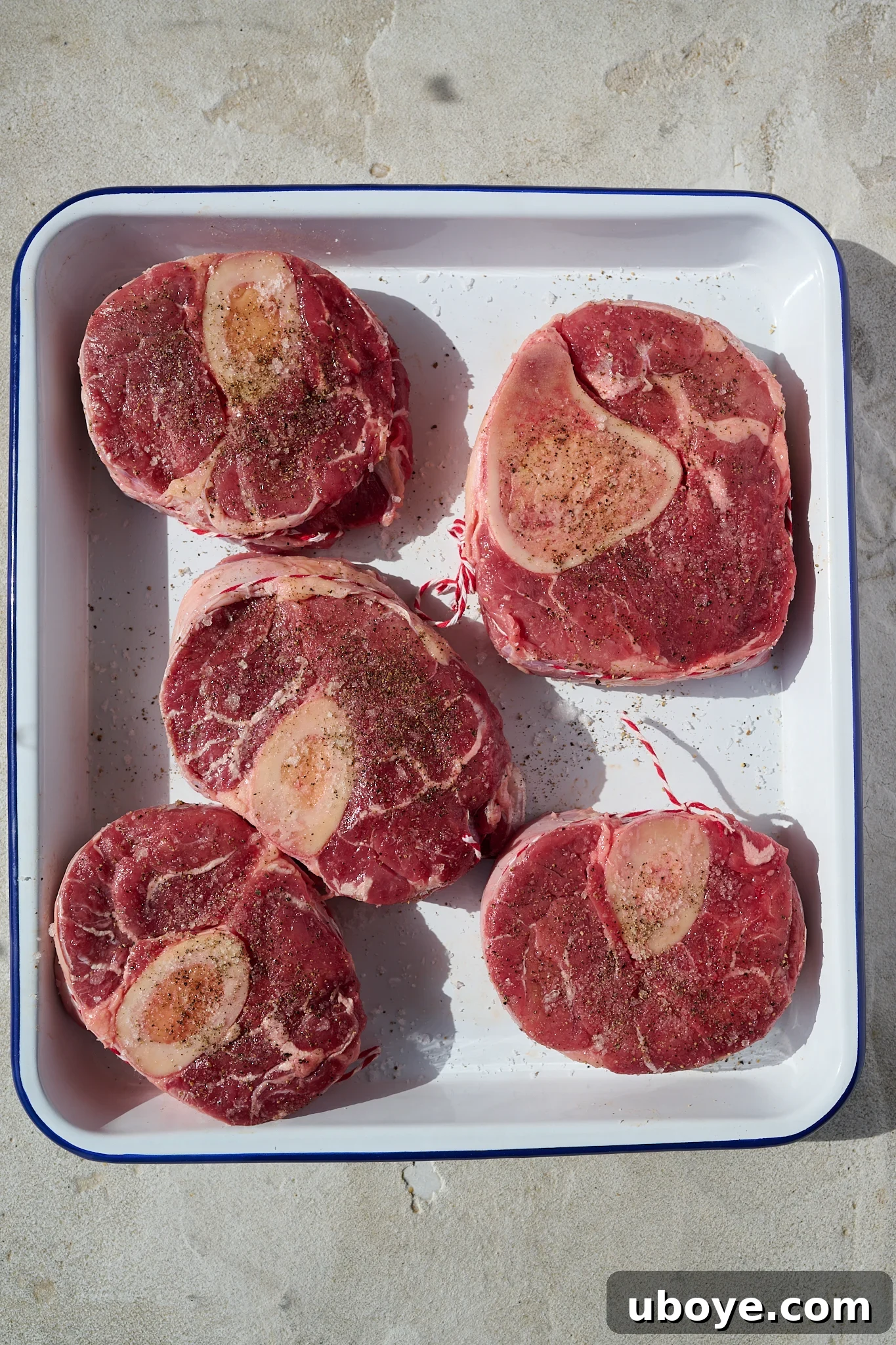 Braised Osso Buco with Zesty Gremolata and Creamy Risotto 4 Veal shanks tied with butchers twine, seasoned with salt and pepper, ready for searing.