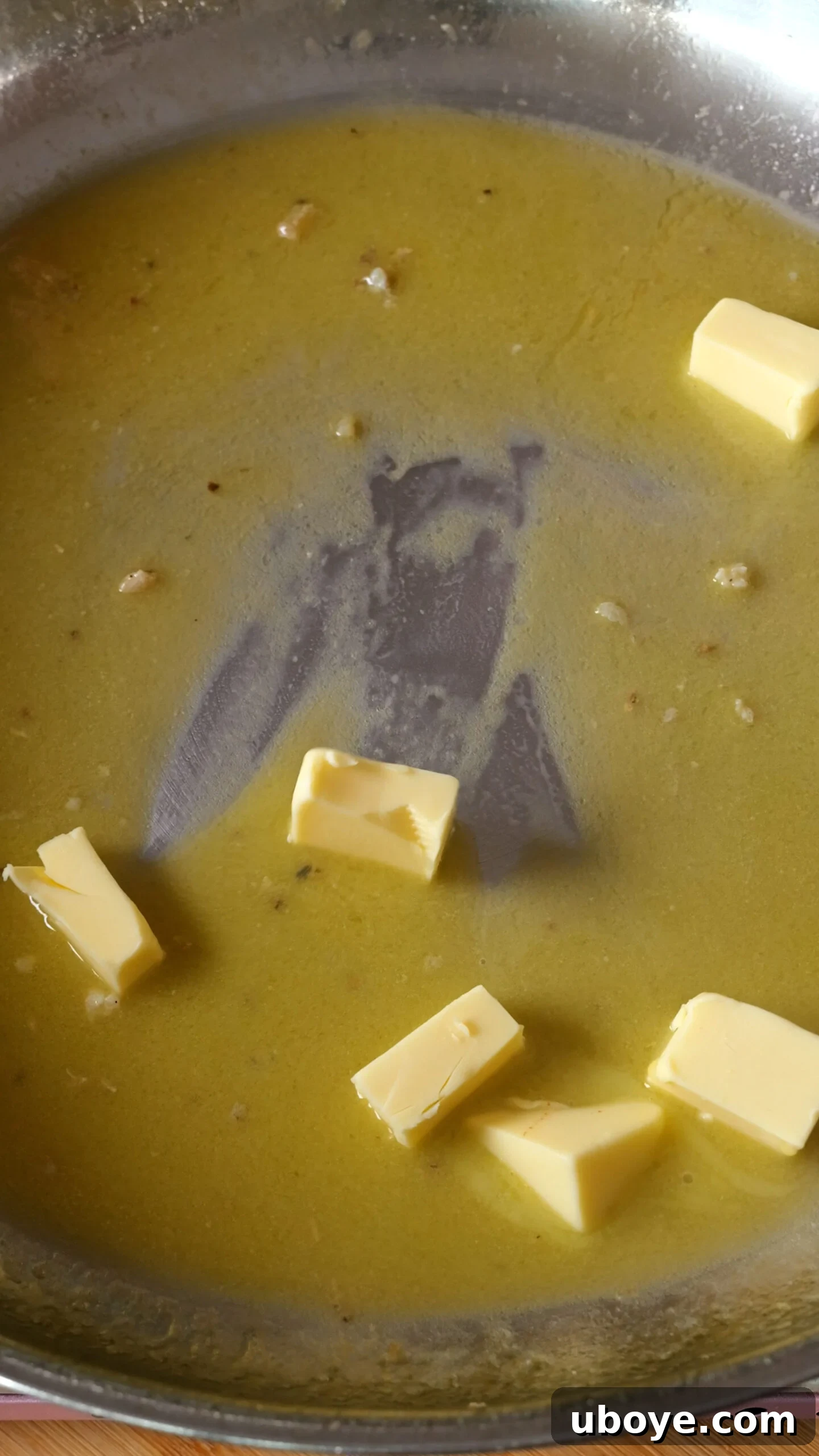 Cubes of butter added to the deglazed pan, melting into the sauce.