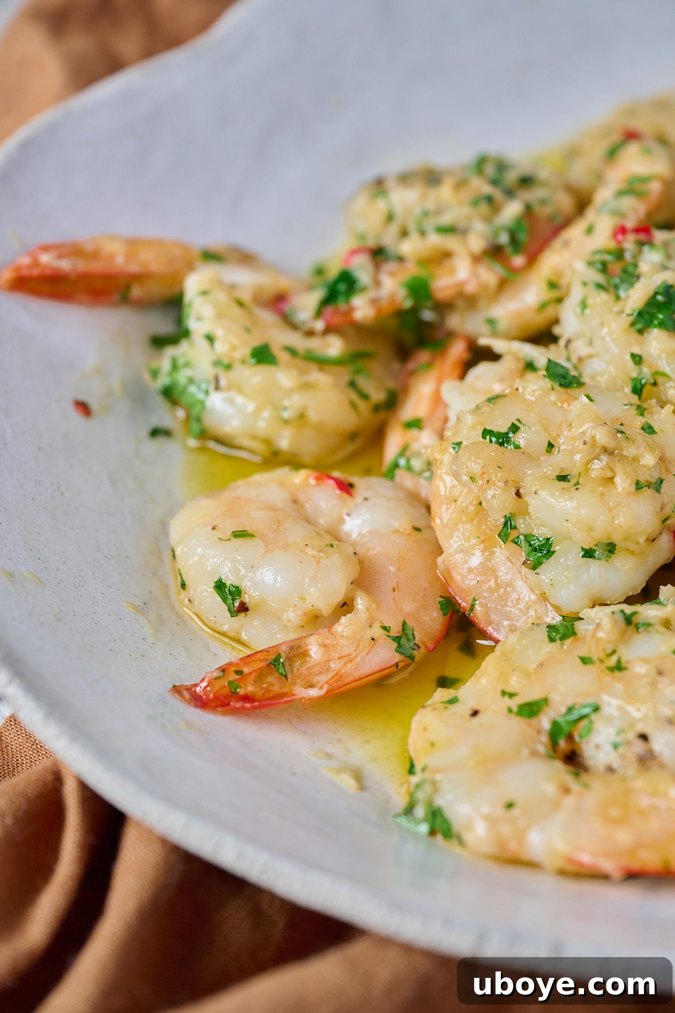 Garlic butter prawns / shrimp are in large white bowl and have fresh parsley sprinkled over top, ready to be served.