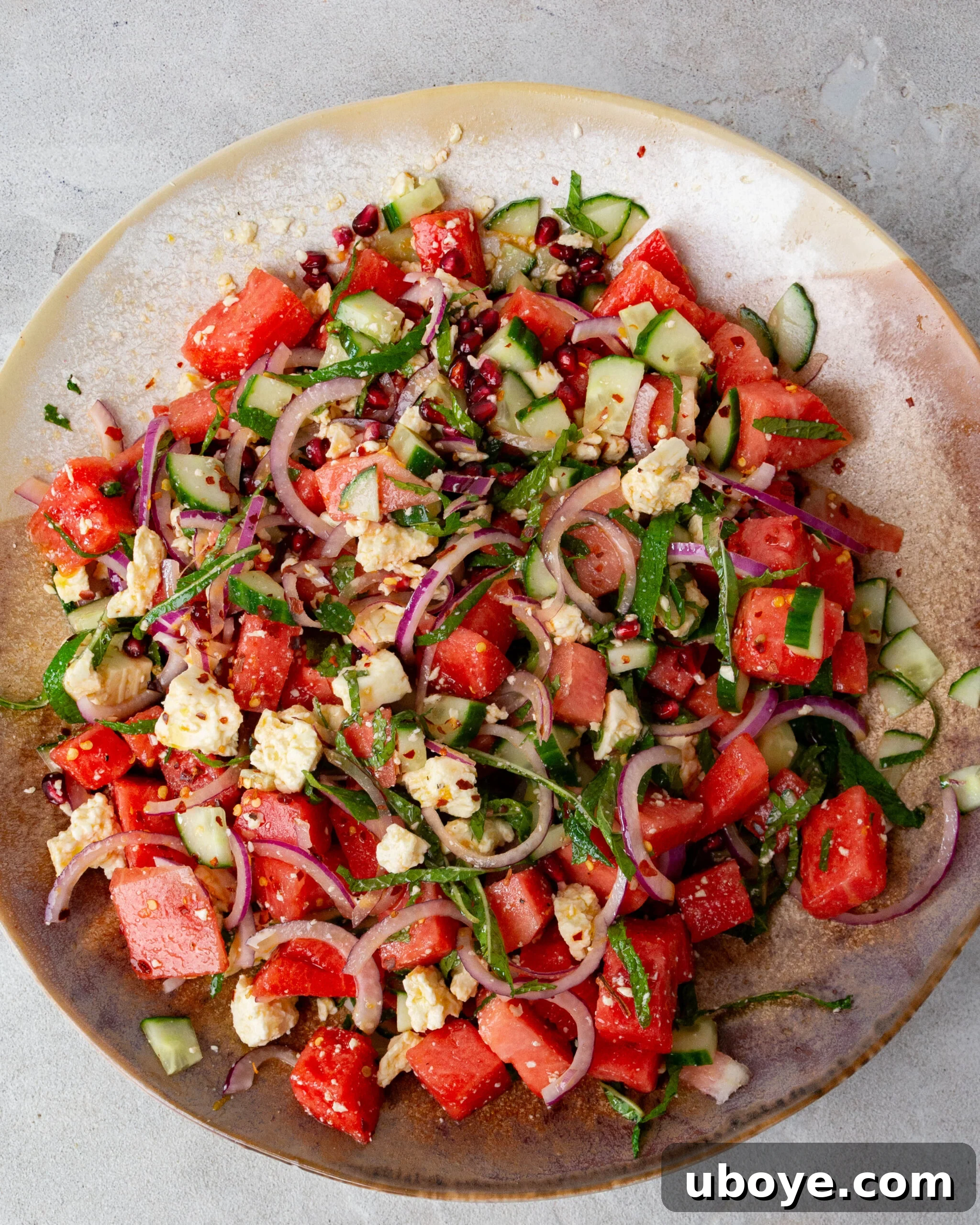 Crisp Watermelon, Feta & Cucumber Medley 2 A large orange bowl brimming with a vibrant Feta, Watermelon & Cucumber Salad, generously garnished with fresh mint leaves.