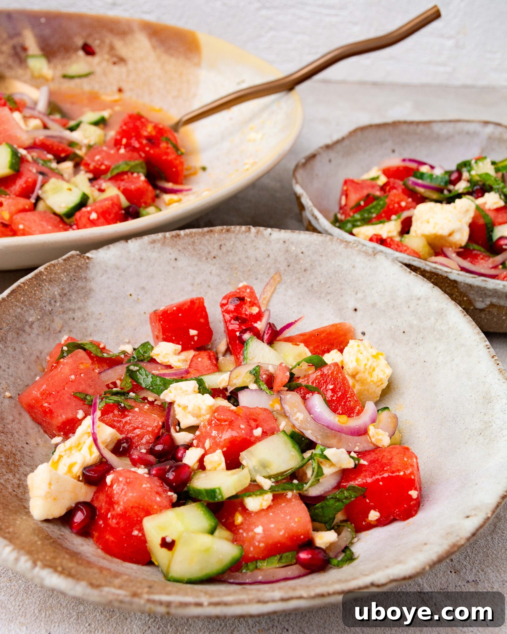 Crisp Watermelon, Feta & Cucumber Medley 8 Three serving bowls of Feta, Watermelon & Cucumber Salad, with a gold spoon elegantly placed in the largest bowl at the back.