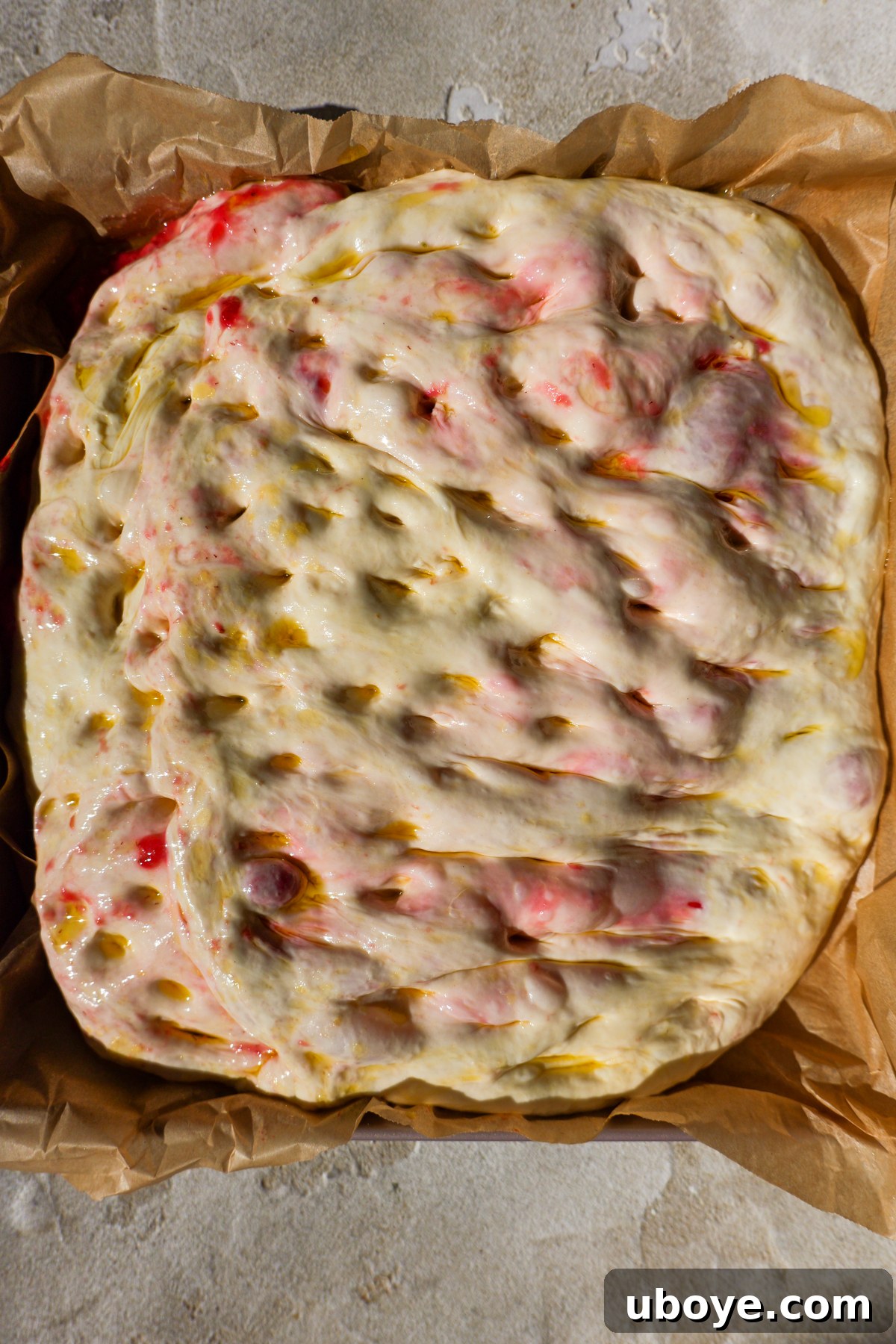 Sweet Focaccia with Strawberry Jam and Cream Cheese Glaze 7 Dough is dimpled and sitting in baking tin.