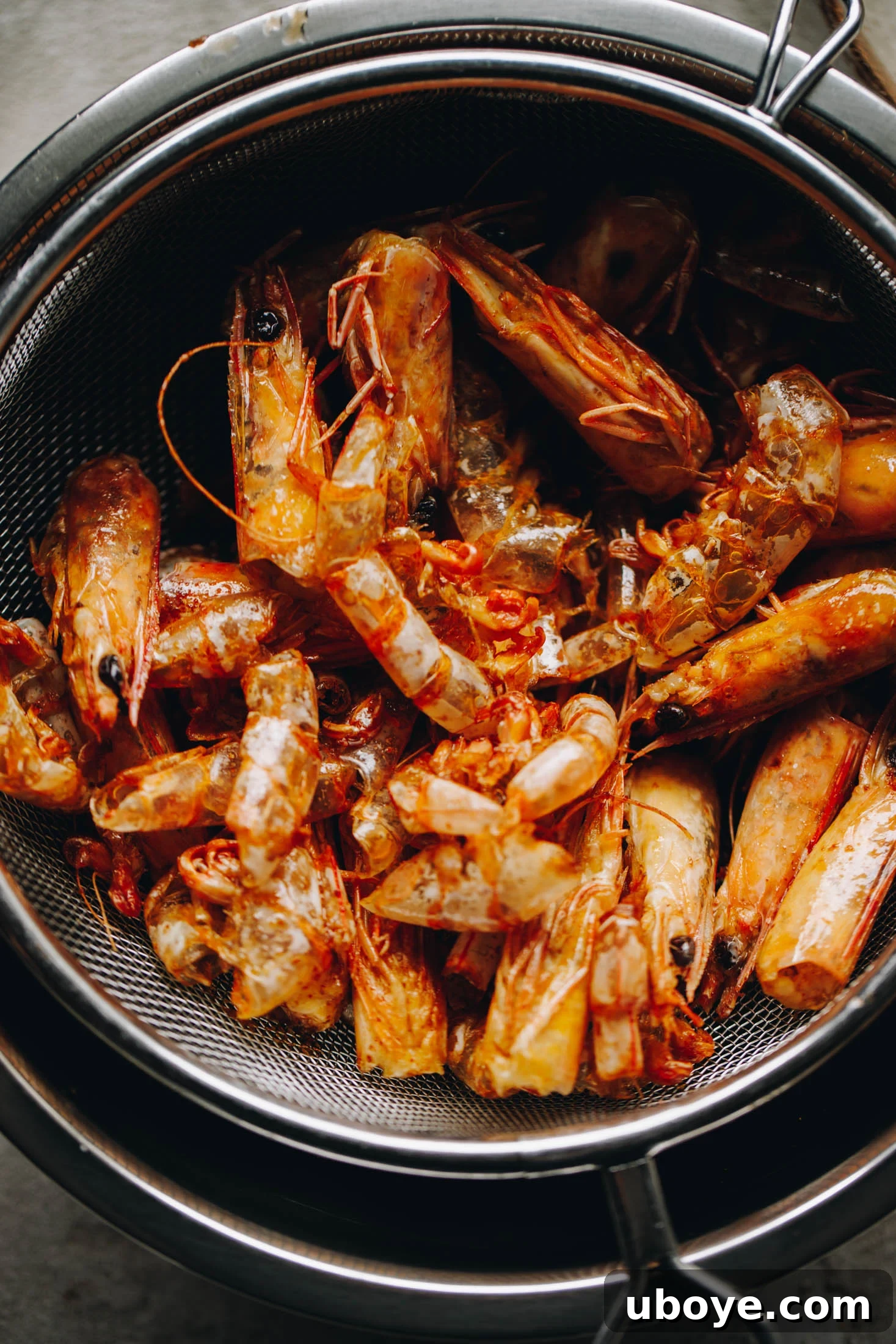 Prawn heads and shells frying in olive oil, turning the oil orange.