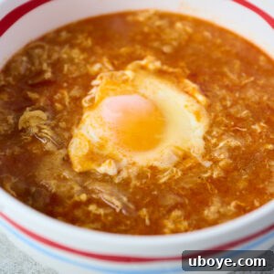 A beautifully presented bowl of Sopa de Ajo, featuring a perfectly poached egg and crusty bread, ready to be enjoyed.