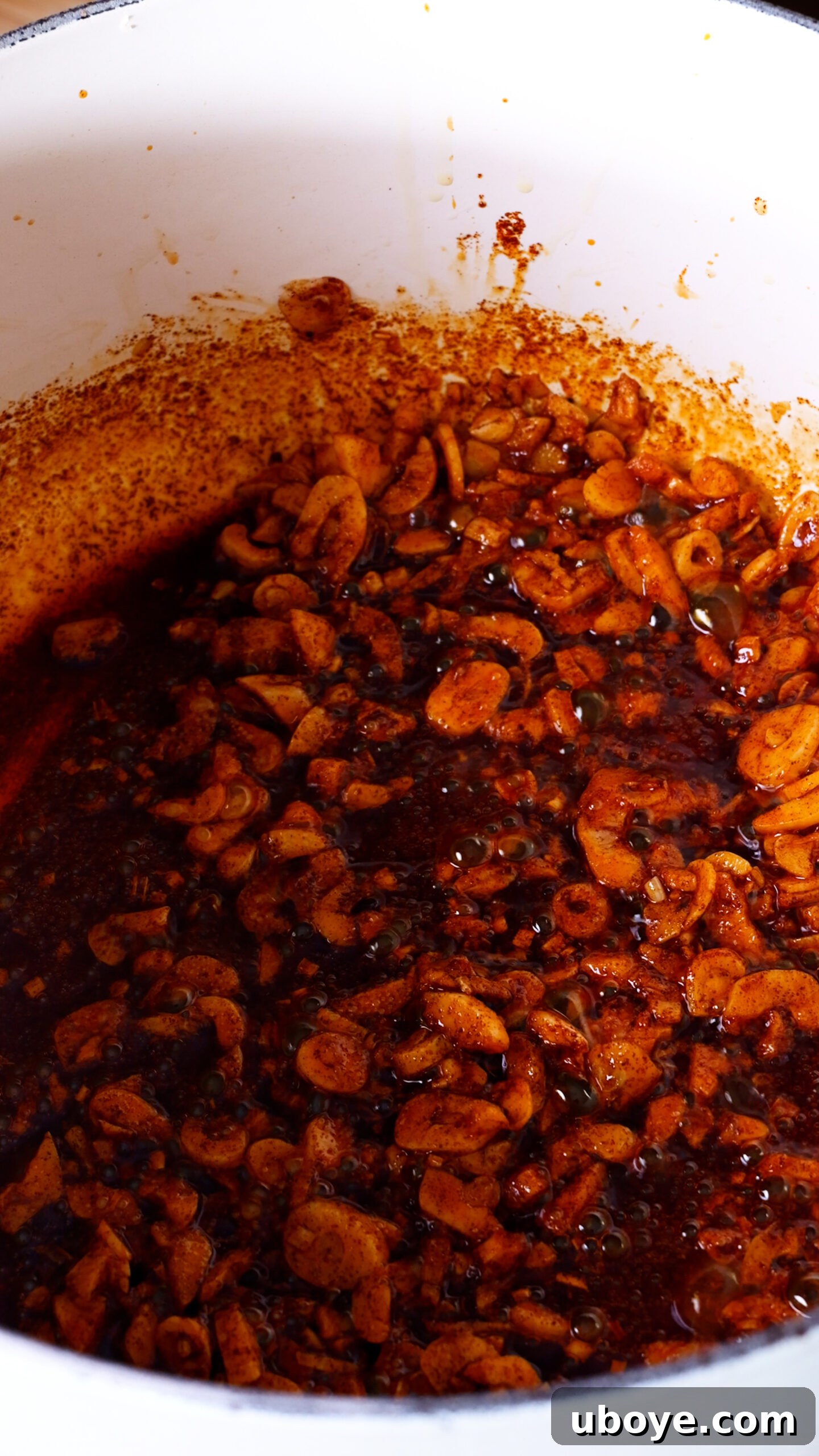 Step 1: Thinly sliced garlic gently frying in golden olive oil in a large pot, with a wooden spoon stirring.