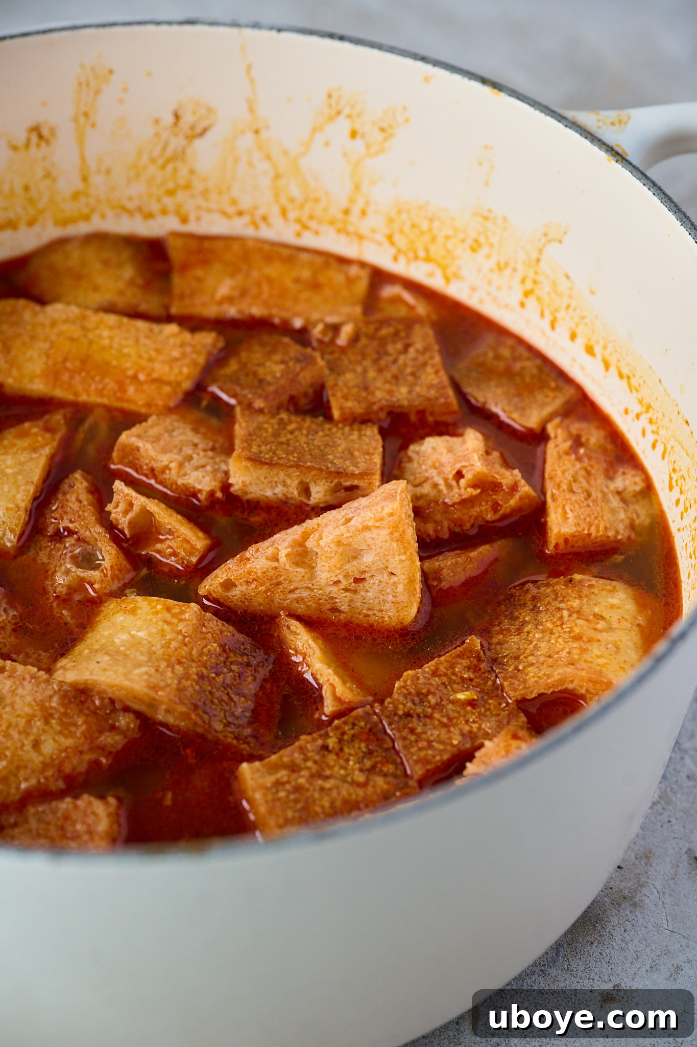 Step 2: Torn pieces of day-old bread being stirred into the pot with sautéed garlic and paprika, followed by pouring in vegetable or chicken broth.