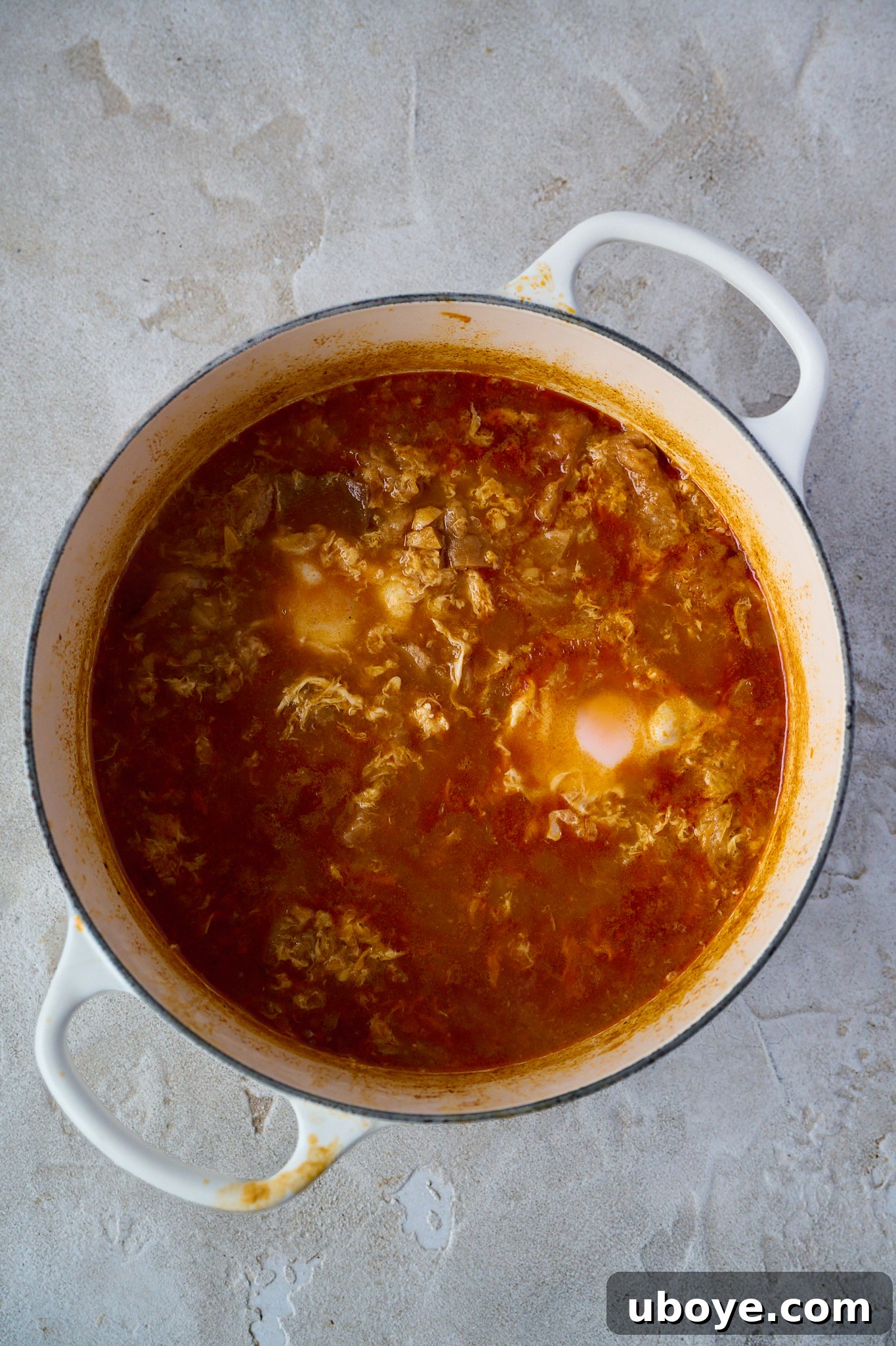 Step 3: Whisked eggs being slowly drizzled into the simmering Sopa de Ajo, then whole eggs cracked into the pot to poach.