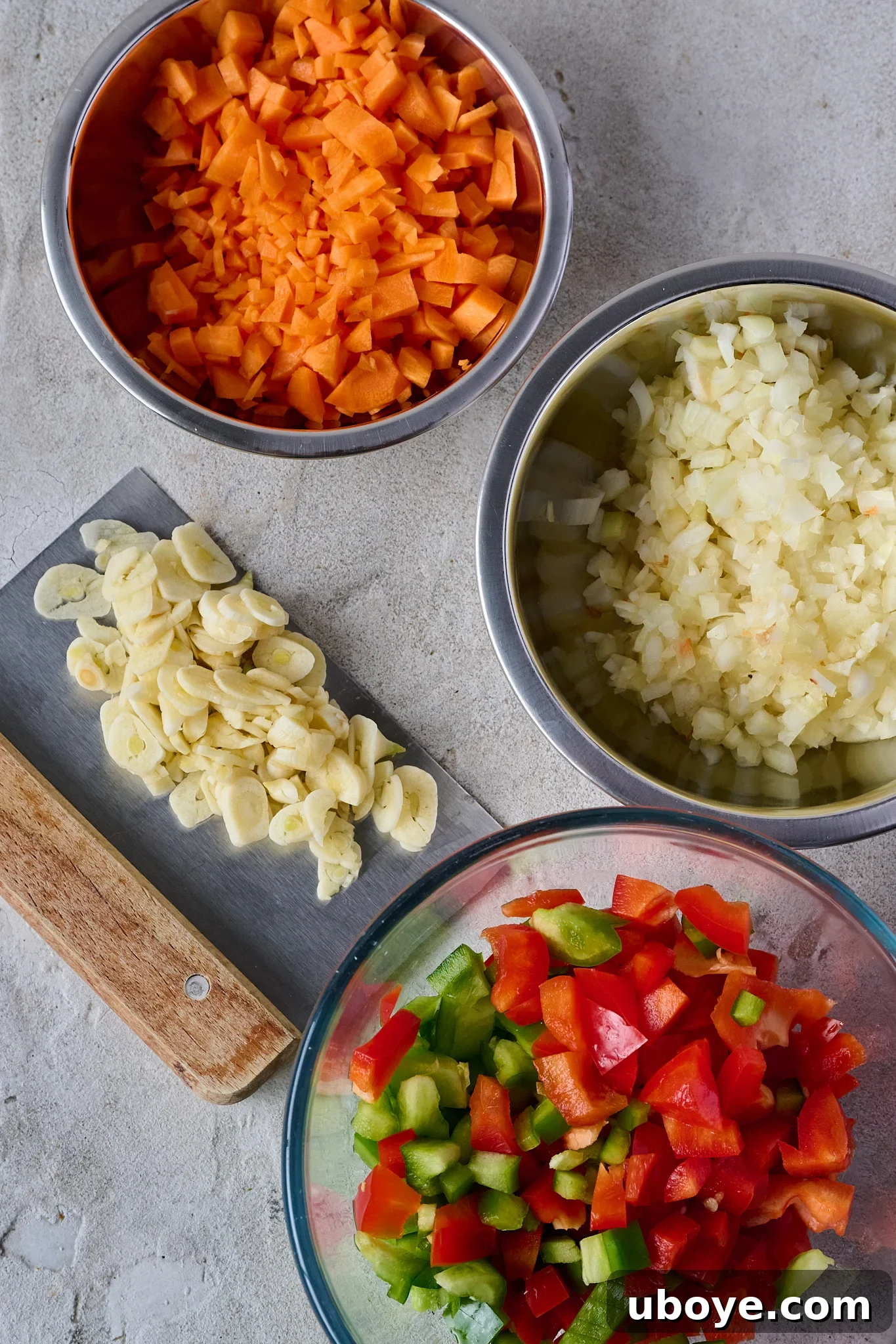 Authentic Vegan Lentejas: A Spanish Comfort Stew 5 Finely chopped carrots, onions, bell peppers (capsicums), and garlic prepared and placed in small stainless steel bowls, ready for the sofrito.
