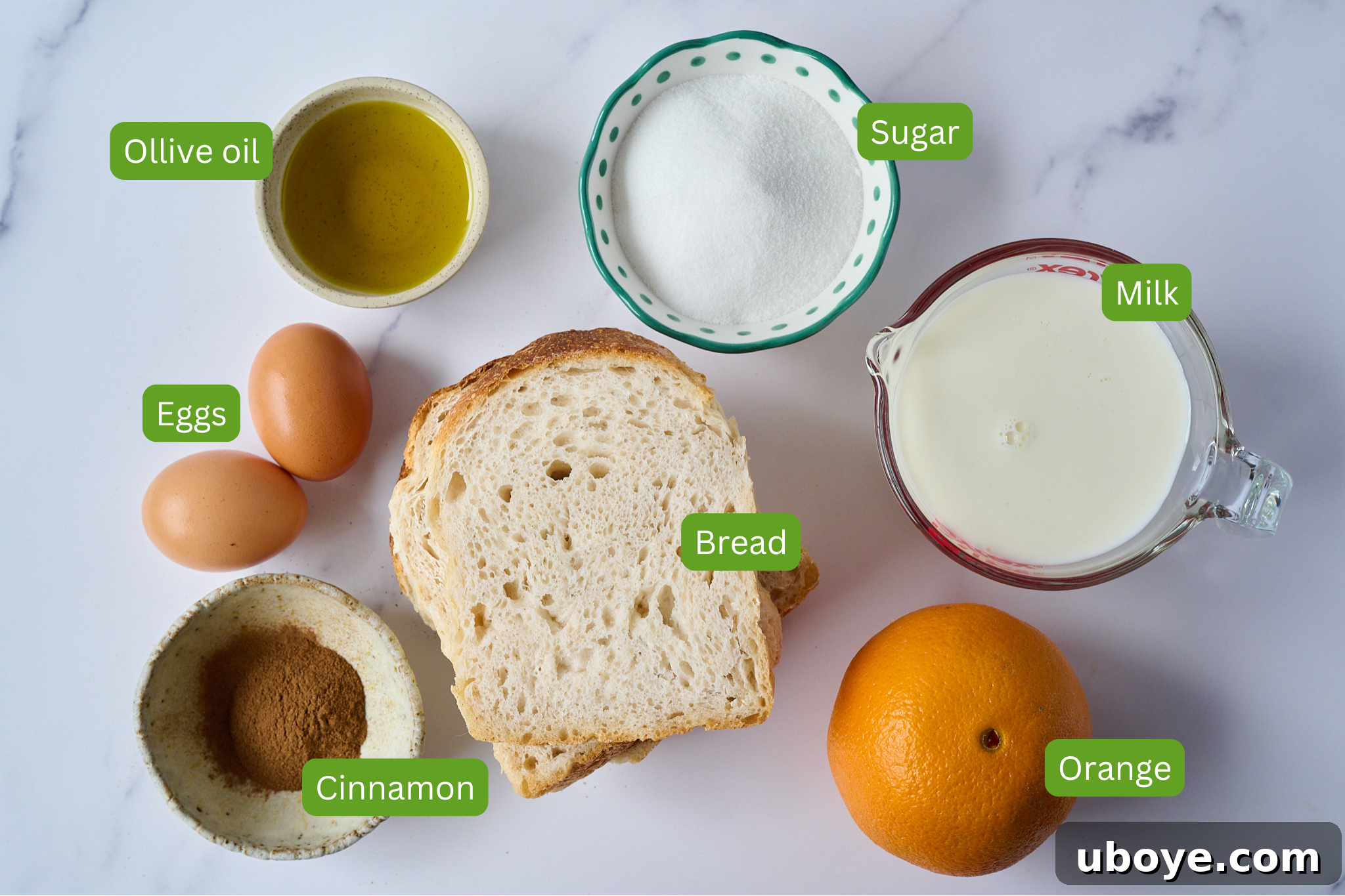 Torrijas Spain's Beloved French Toast 4 Fresh ingredients laid out on a kitchen counter: thick slices of day-old bread, a bowl of fresh milk, vibrant orange peels, eggs, and a bottle of extra virgin olive oil, ready for making Torrijas.