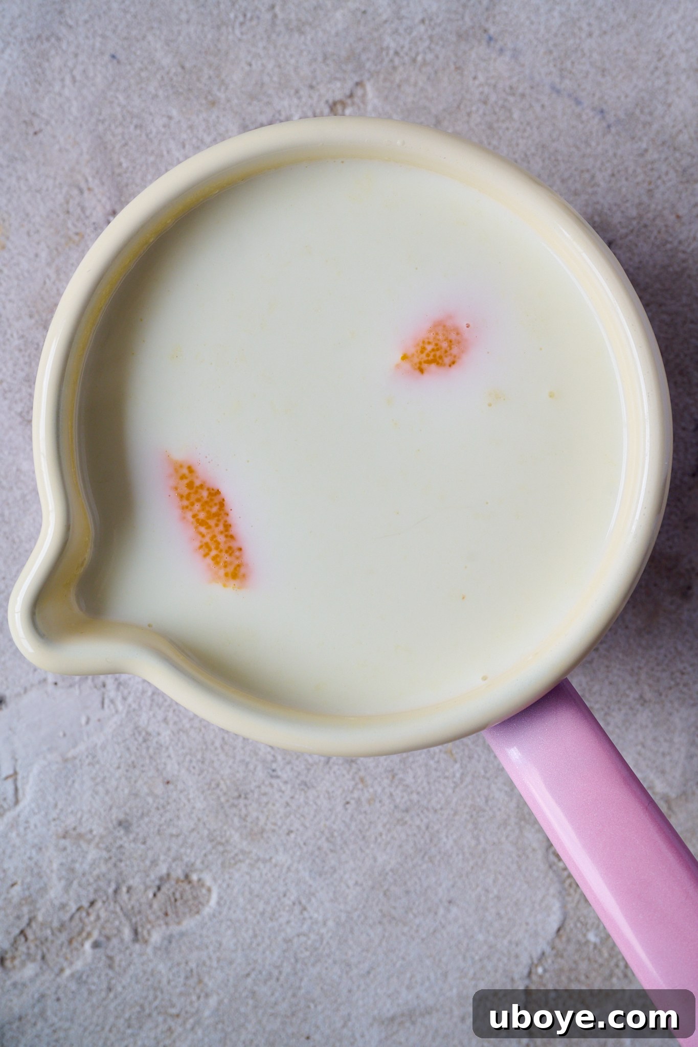 Torrijas Spain's Beloved French Toast 5 A small pink saucepan gently simmers milk infused with vibrant orange peel, filling the kitchen with a sweet, citrusy aroma.