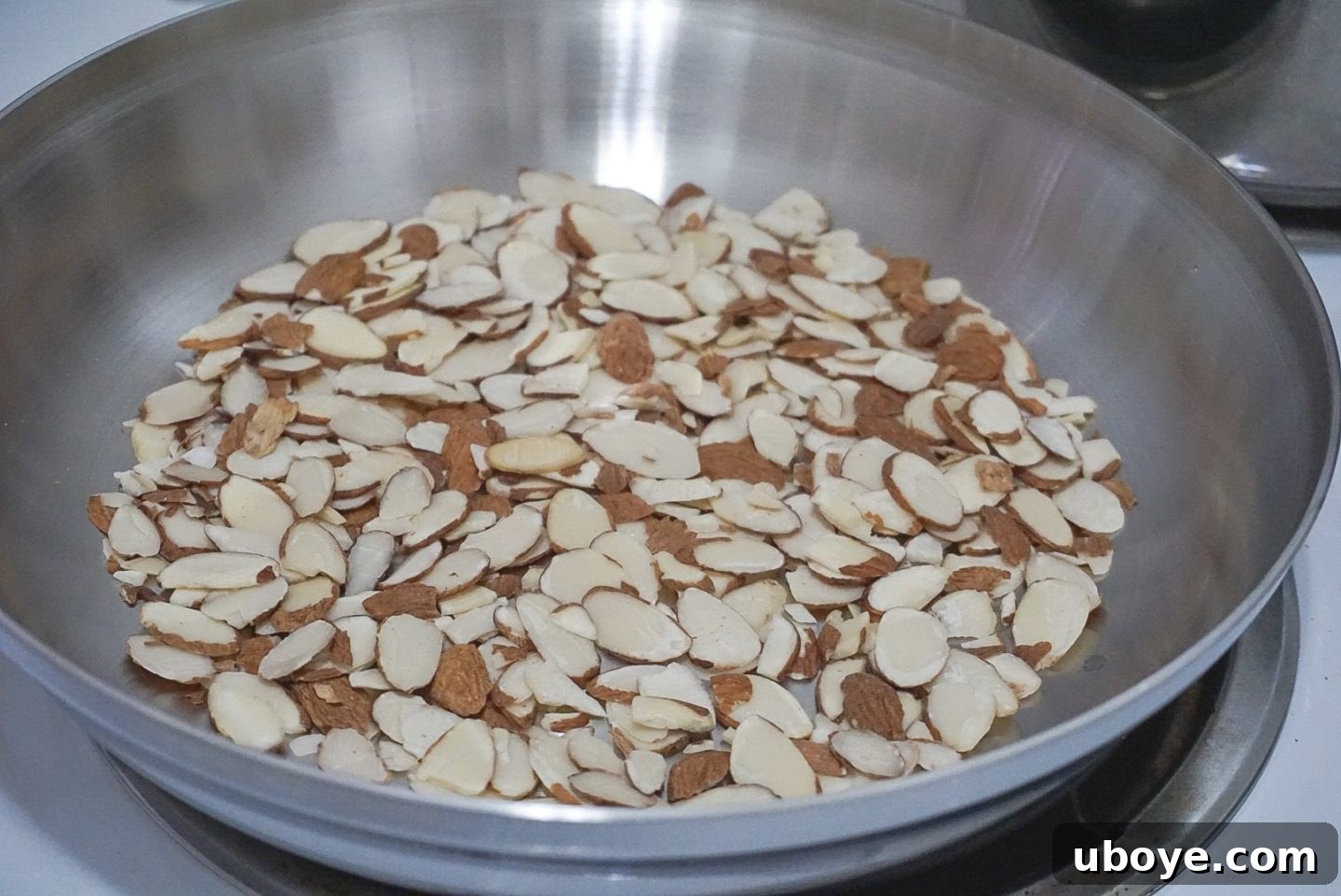 Sliced almonds toasting in a dry skillet, turning golden brown.