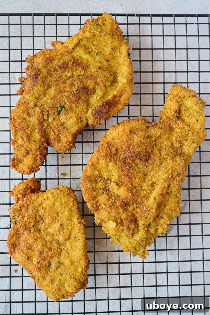 Three pieces of crispy breaded chicken laying on cooling rack. 