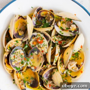A bowl of garlic butter pipis (clams) garnished with fresh herbs.