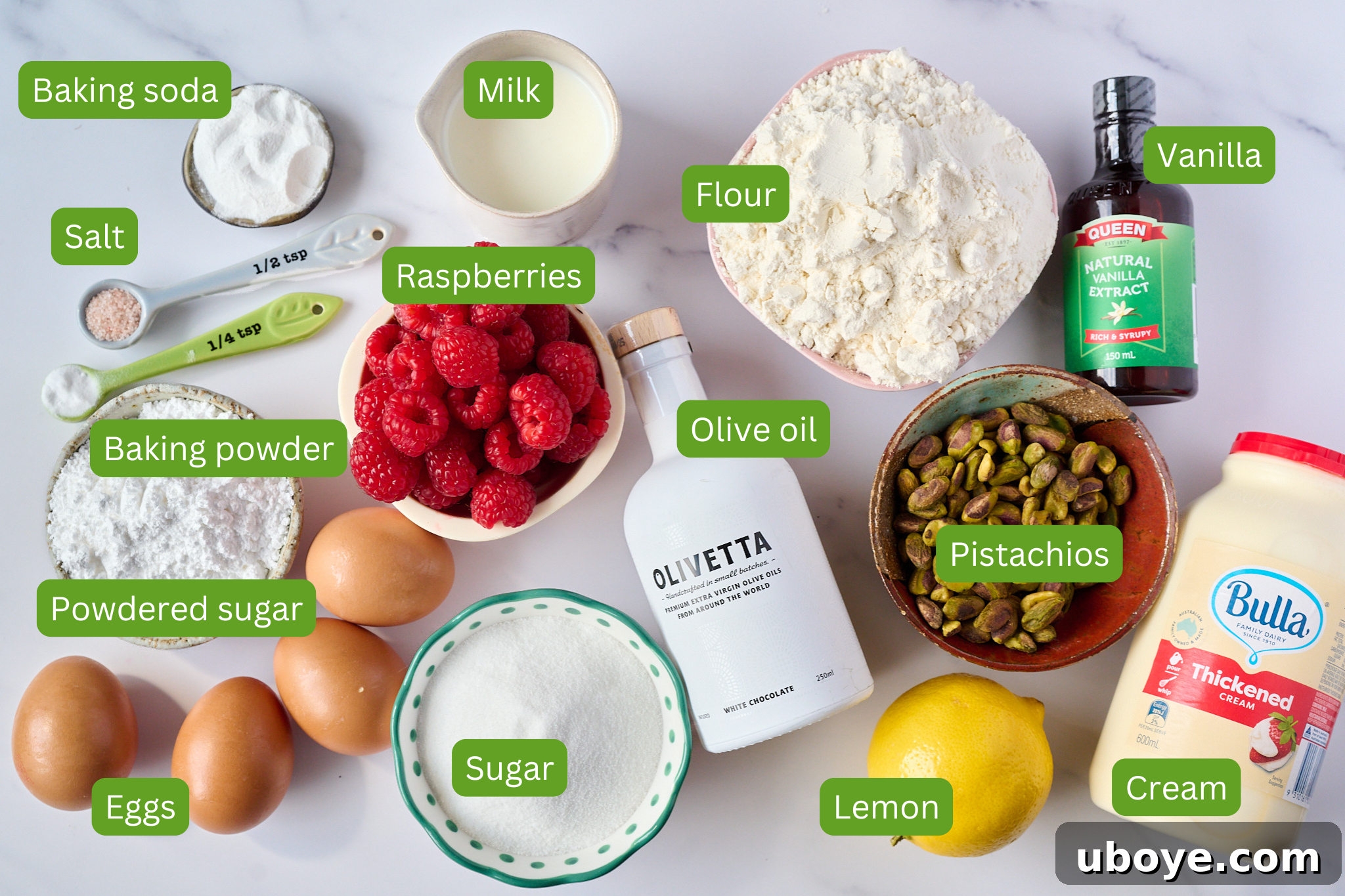 Velvet Olive Oil Cake with Pistachio, Raspberry and White Chocolate 4 A flat lay photograph showcasing the key ingredients for the cake: white chocolate olive oil, fresh raspberries, pistachios, and other baking essentials.