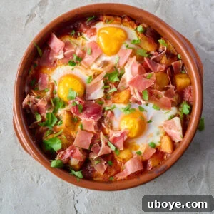 Spanish Baked Eggs (Huevos a la Flamenca) with chorizo, paprika, jamon, tomatoes, onion, garlic, and crispy fried potatoes