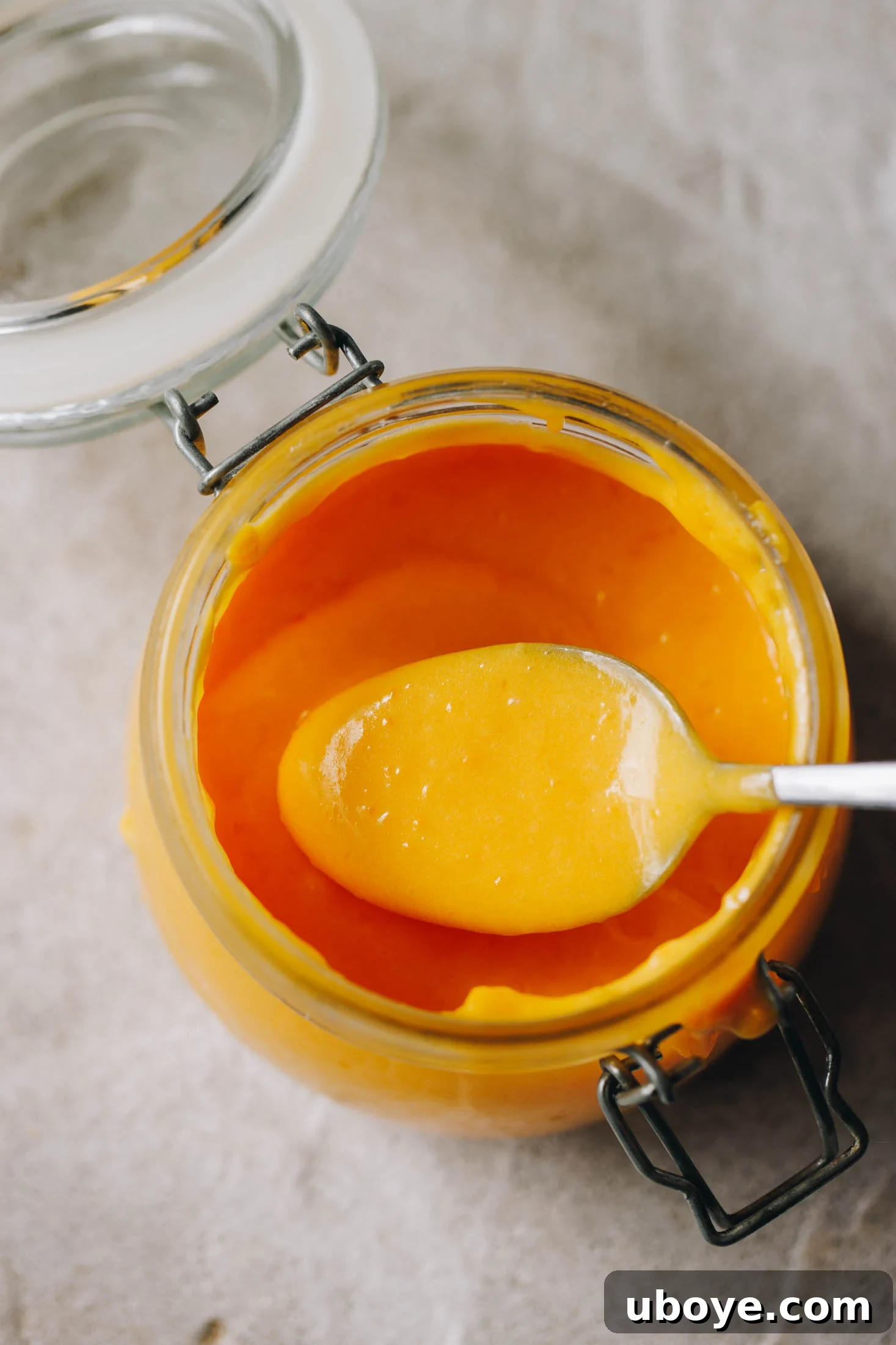 A beautifully presented jar of homemade lemon curd with a spoon, highlighting its vibrant color and smooth texture.