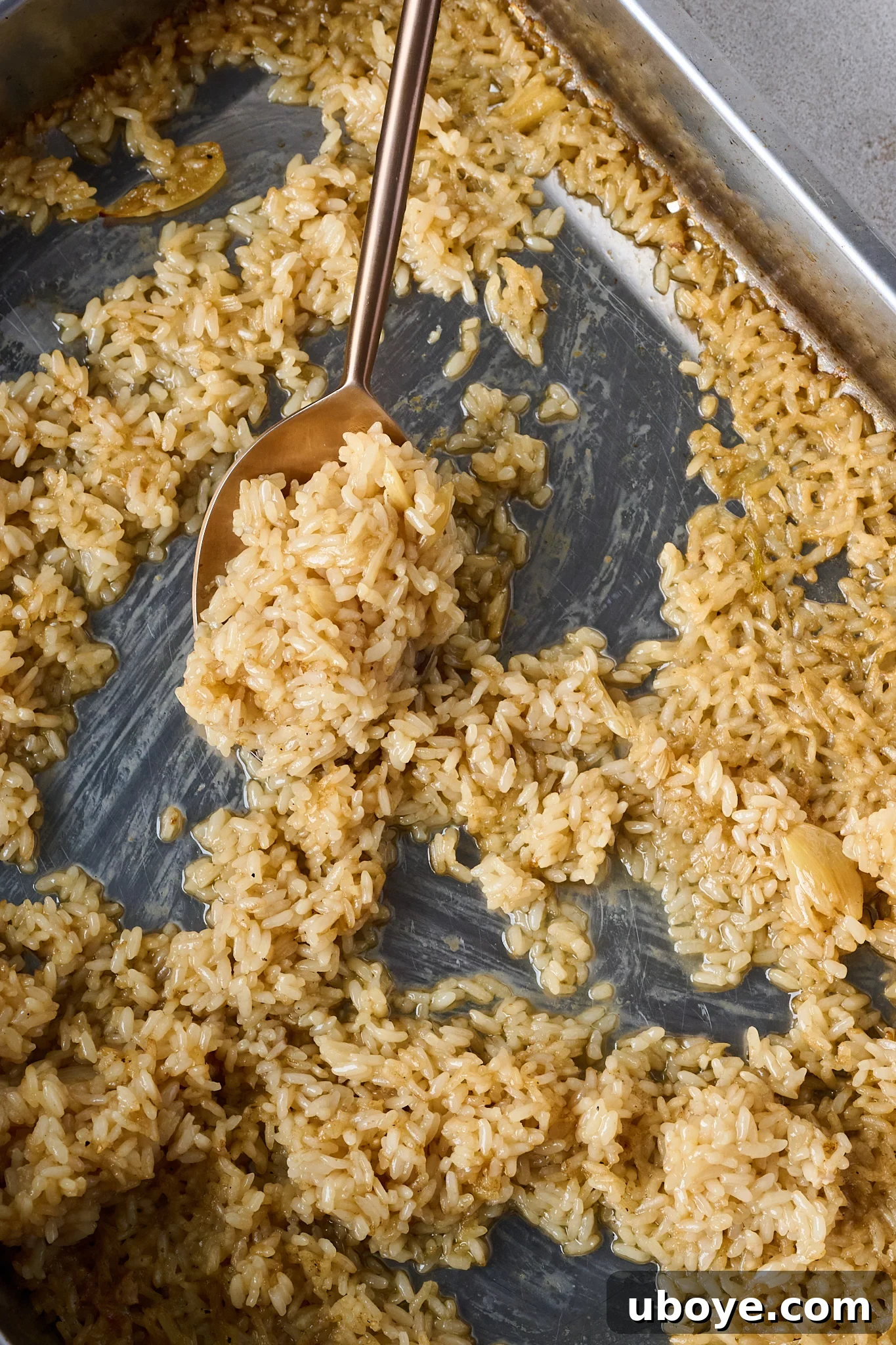 Golden Chicken & Fragrant Garlic Rice Skillet 7 Cooked rice is in baking tray with golden spoon