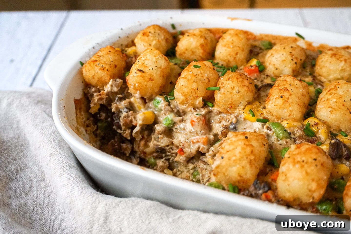 A close-up view of the perfectly golden-brown and crispy tater tots on top of the casserole, indicating delicious texture.
