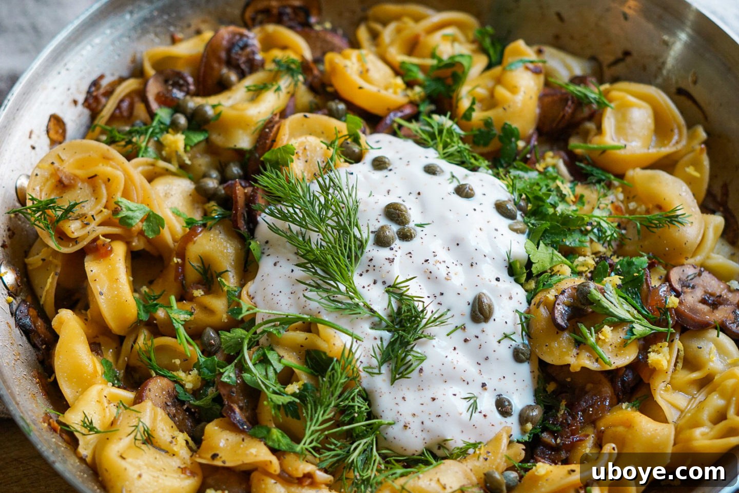 A bowl of fresh ingredients for the vegan tortellini recipe, including lemon, dill, garlic, and mushrooms.