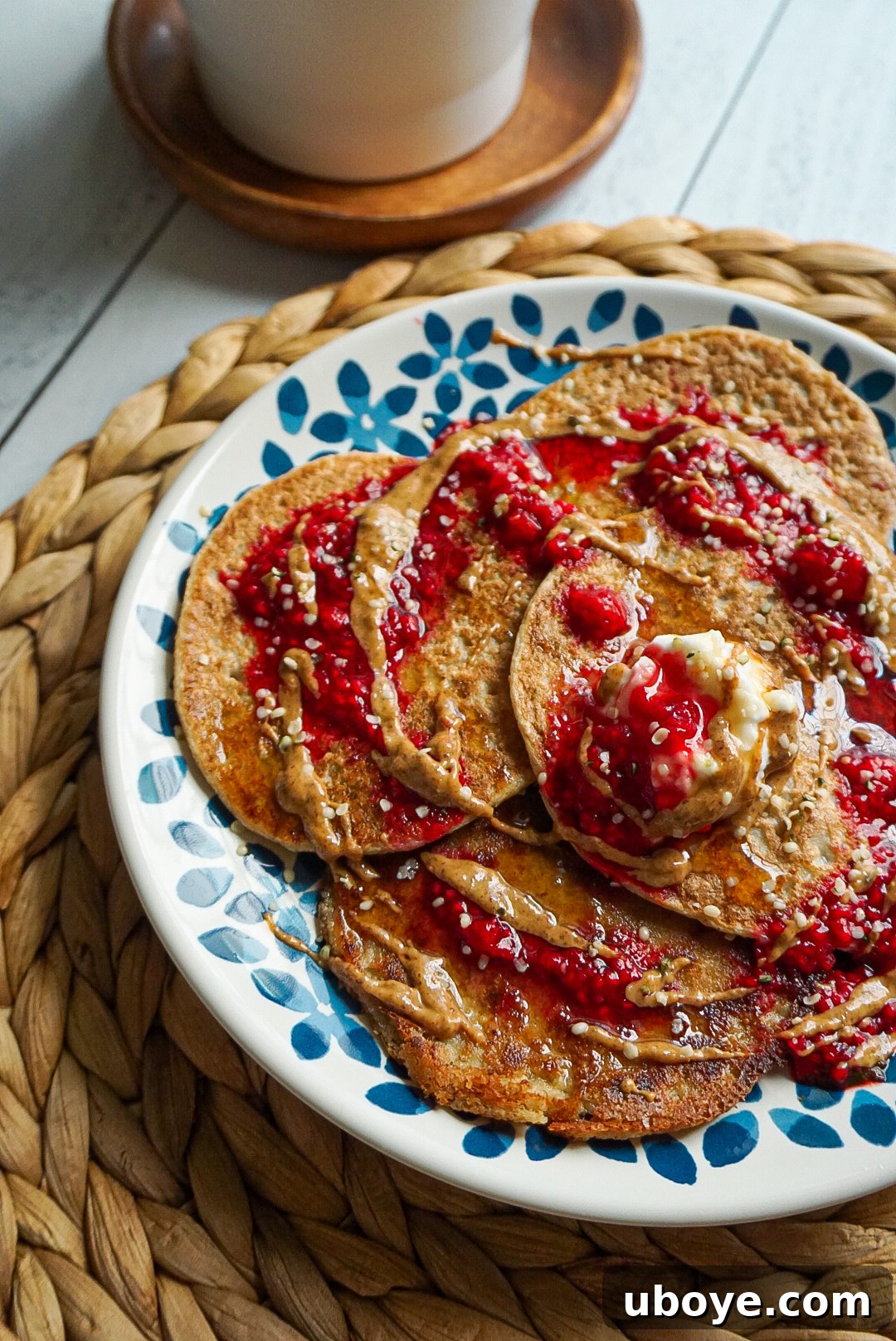 Fluffy 4-Ingredient Pancakes 2 A stack of fluffy vegan banana oat pancakes topped with almond butter and fresh raspberries.