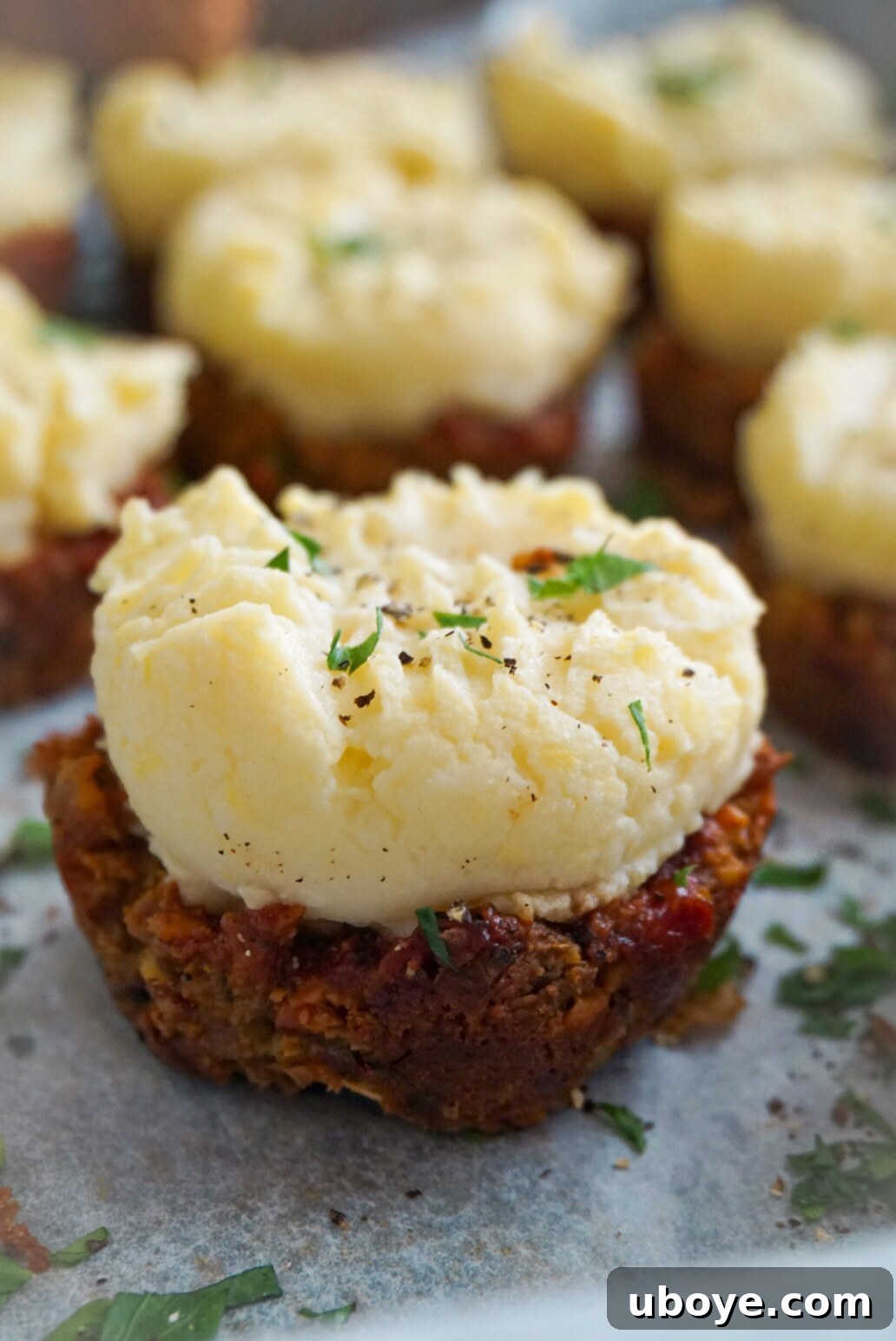 Savory Meatloaf Cupcakes 3 Two hands reaching for a perfectly golden-brown vegan meatloaf muffin, freshly baked.
