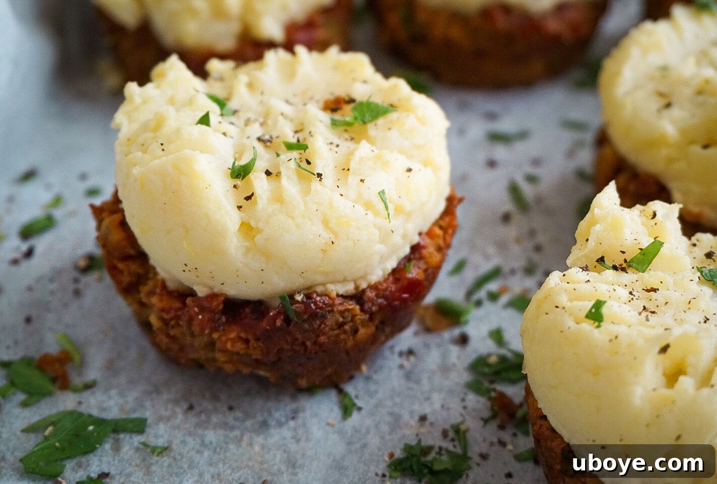 Savory Meatloaf Cupcakes 7 A beautifully plated serving of vegan meatloaf muffins topped with mashed potatoes and fresh herbs, ready to be enjoyed.