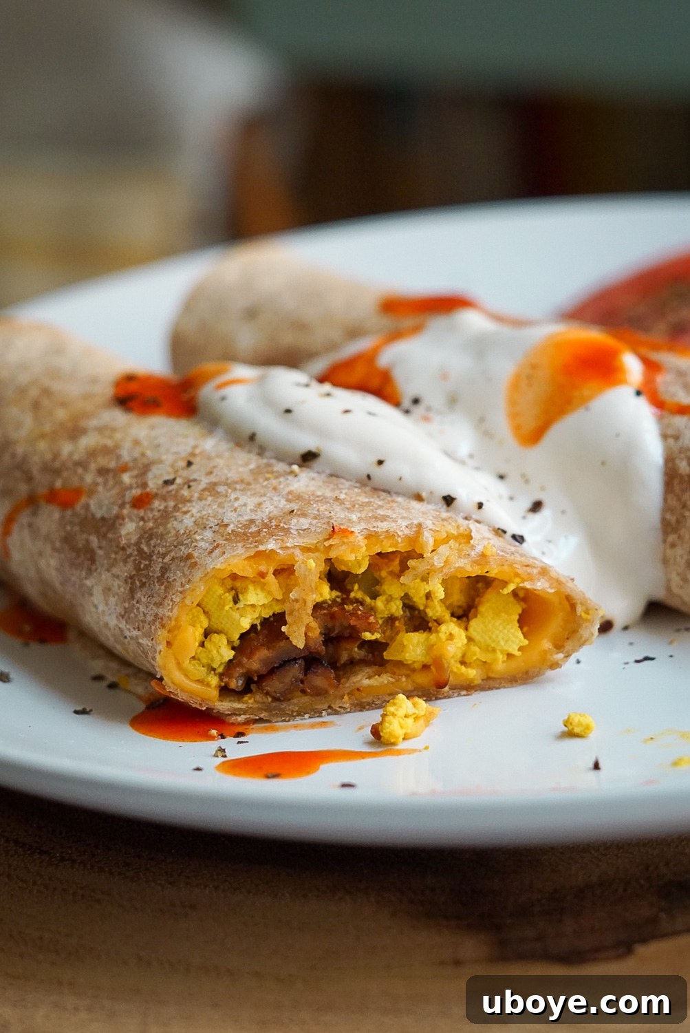 Golden Bacon Cheddar Breakfast Bites 3 Close-up of baked vegan breakfast taquitos with sauce