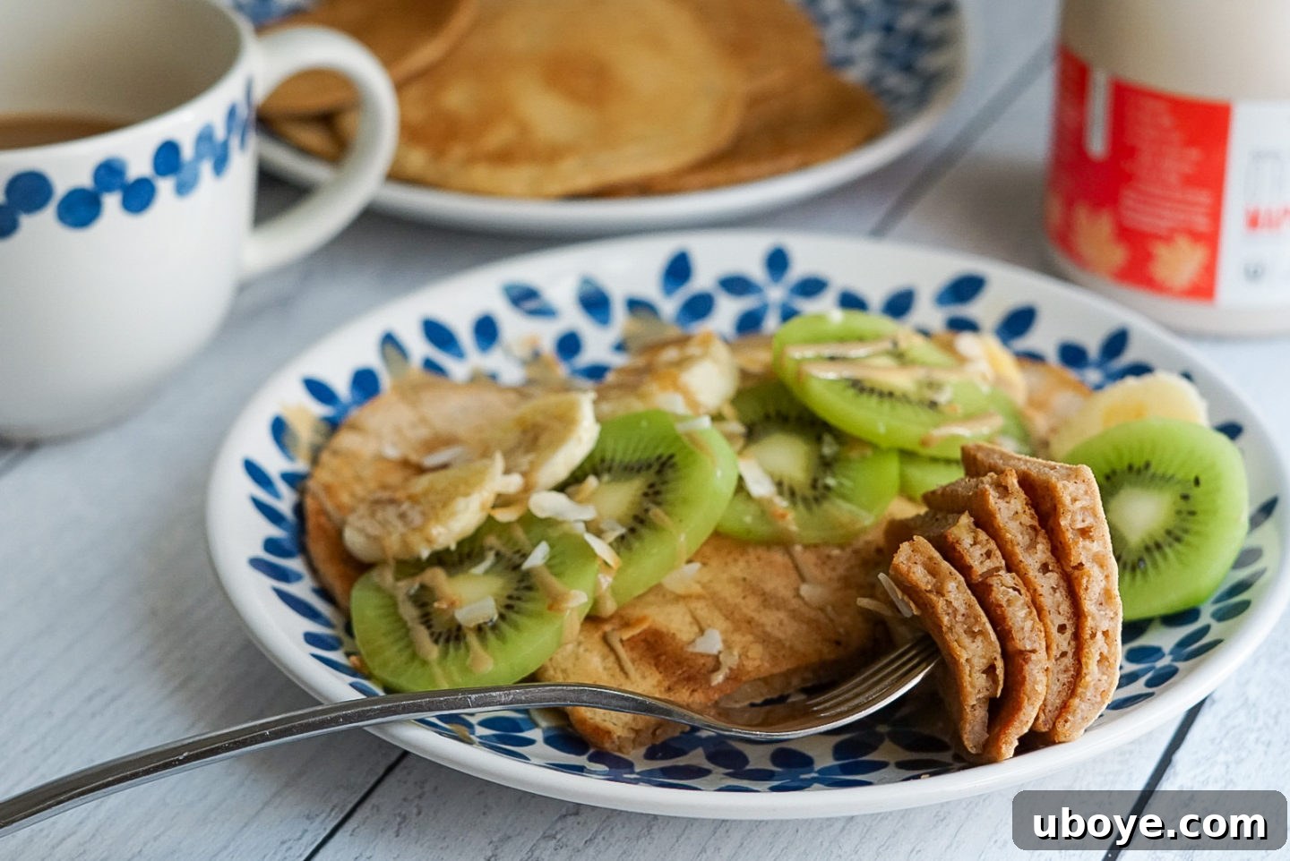 A vibrant, close-up image of a single vegan mango pancake topped with fresh fruit and coconut, ready to be enjoyed.