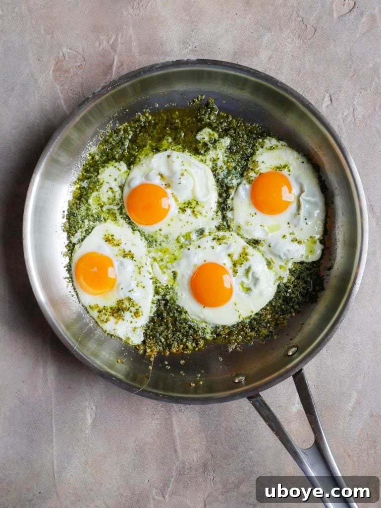 Pesto-Kissed Eggs 3 Close-up shot of freshly cooked pesto eggs sizzling in a pan with vibrant green pesto