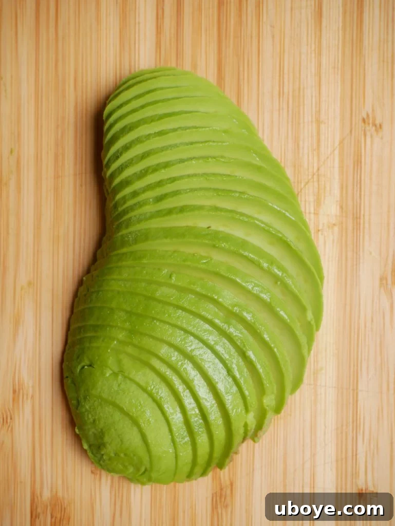 A top-down view of the ultimate avocado toast, showing thick slices of avocado fanned out on toasted sourdough, garnished with spices.