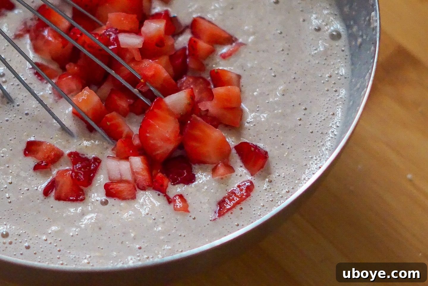 muffin batter in a mixing bowl with fresh strawberries folded in, ready for baking