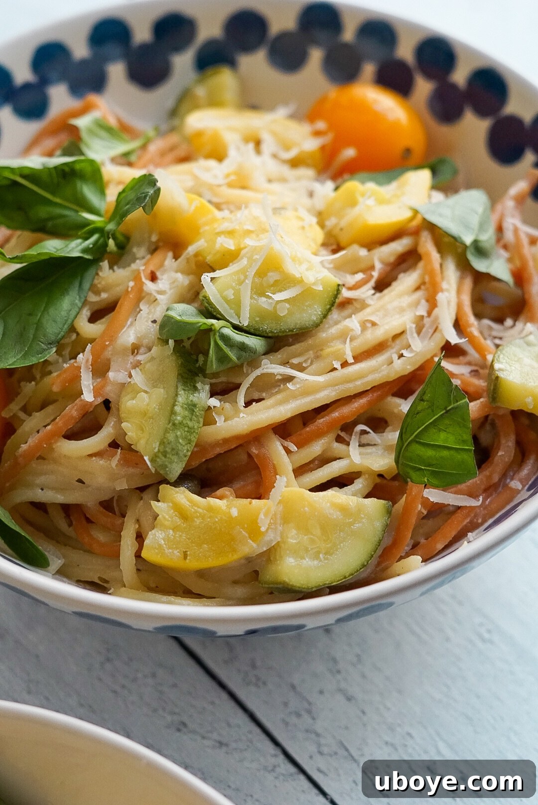 A vibrant display of fresh basil, lemon halves, garlic cloves, vegan feta, and vegan parmesan cheese.
