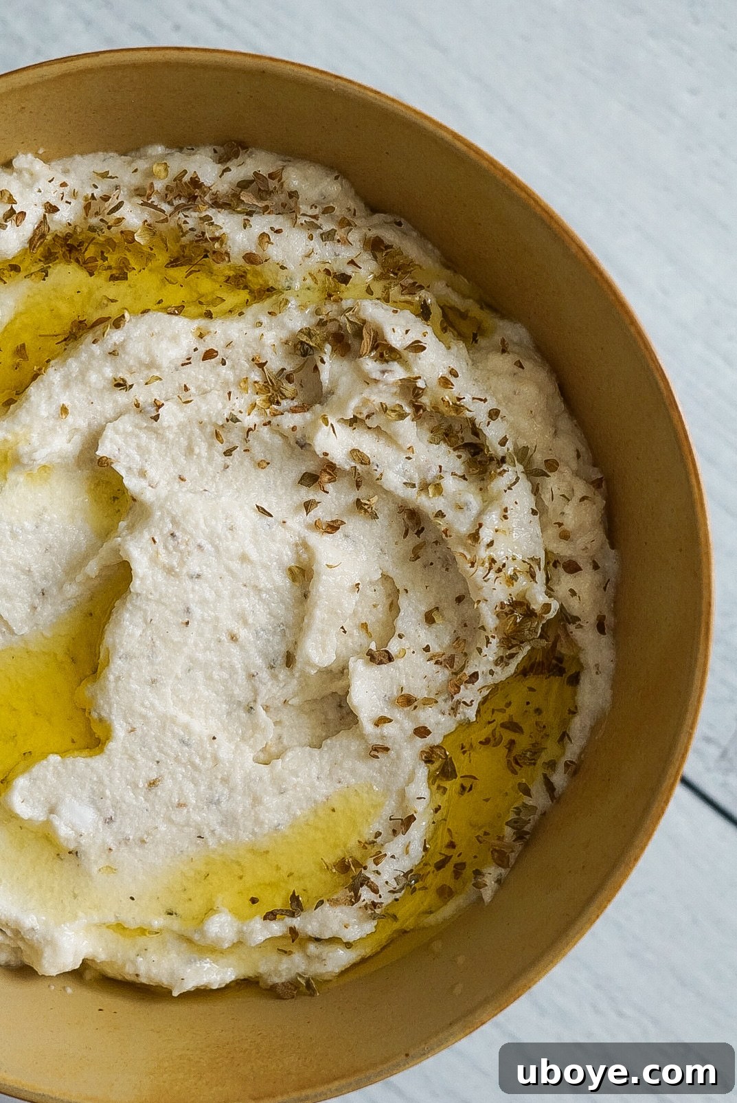 Vegan Whipped Feta Dip served on a plate with fresh herbs