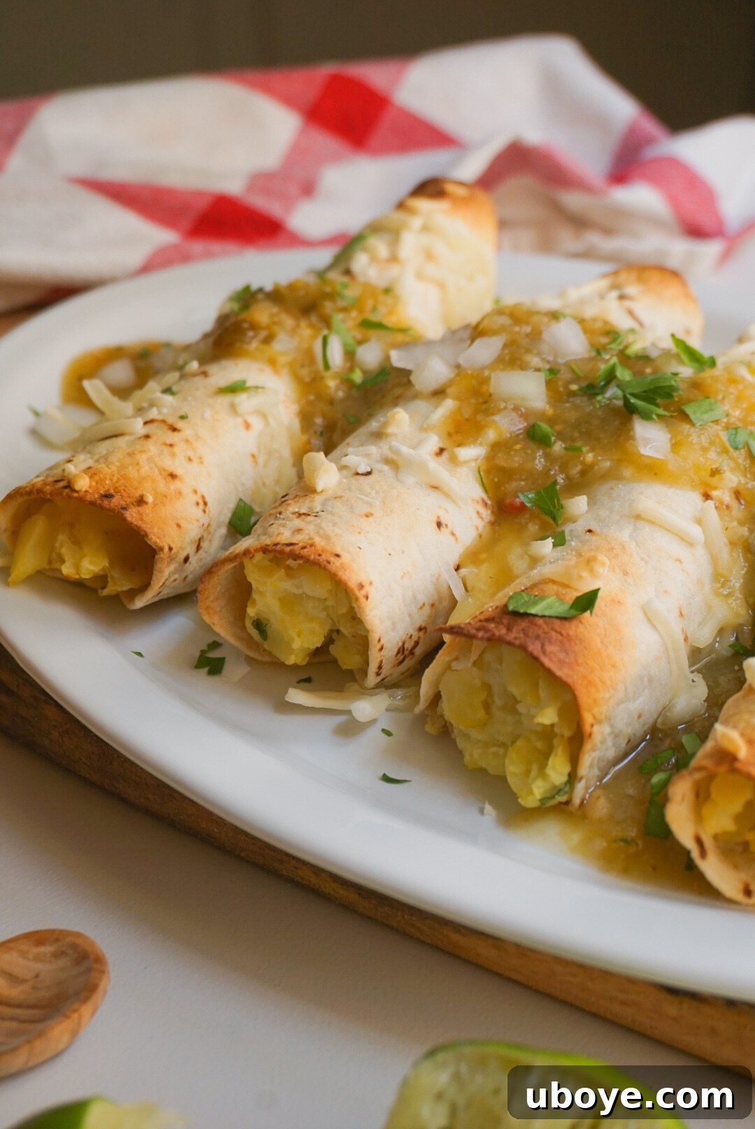 Golden Oven-Baked Potato Taquitos 4 A stack of golden brown baked vegan potato taquitos on a rustic plate
